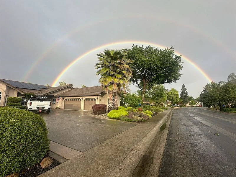 Redding neighborhood with a rainbow behind a house and trees