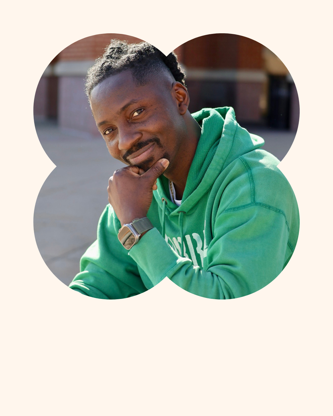 Portrait of a man in a green hoodie, resting his chin on his hand with a thoughtful expression, outdoors.