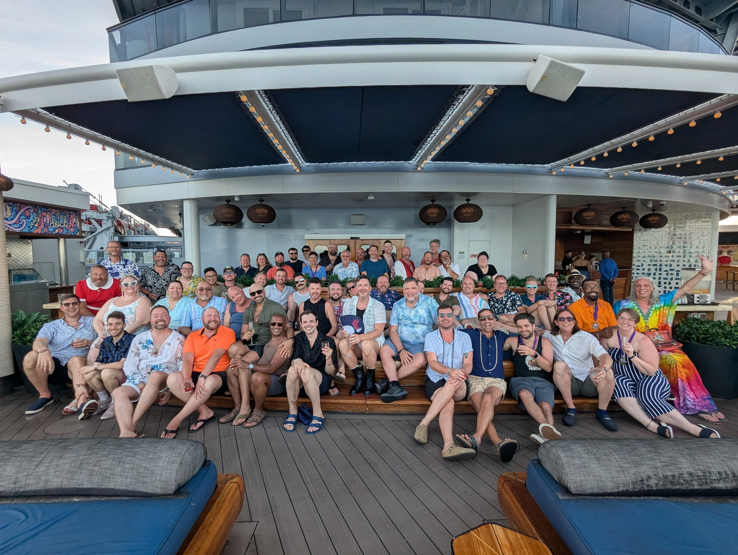 A large group of Sailors from the 2025 Big Fabulous Cruise gathered together on a deck with a cruise ship background, smiling and posing for a group photo.