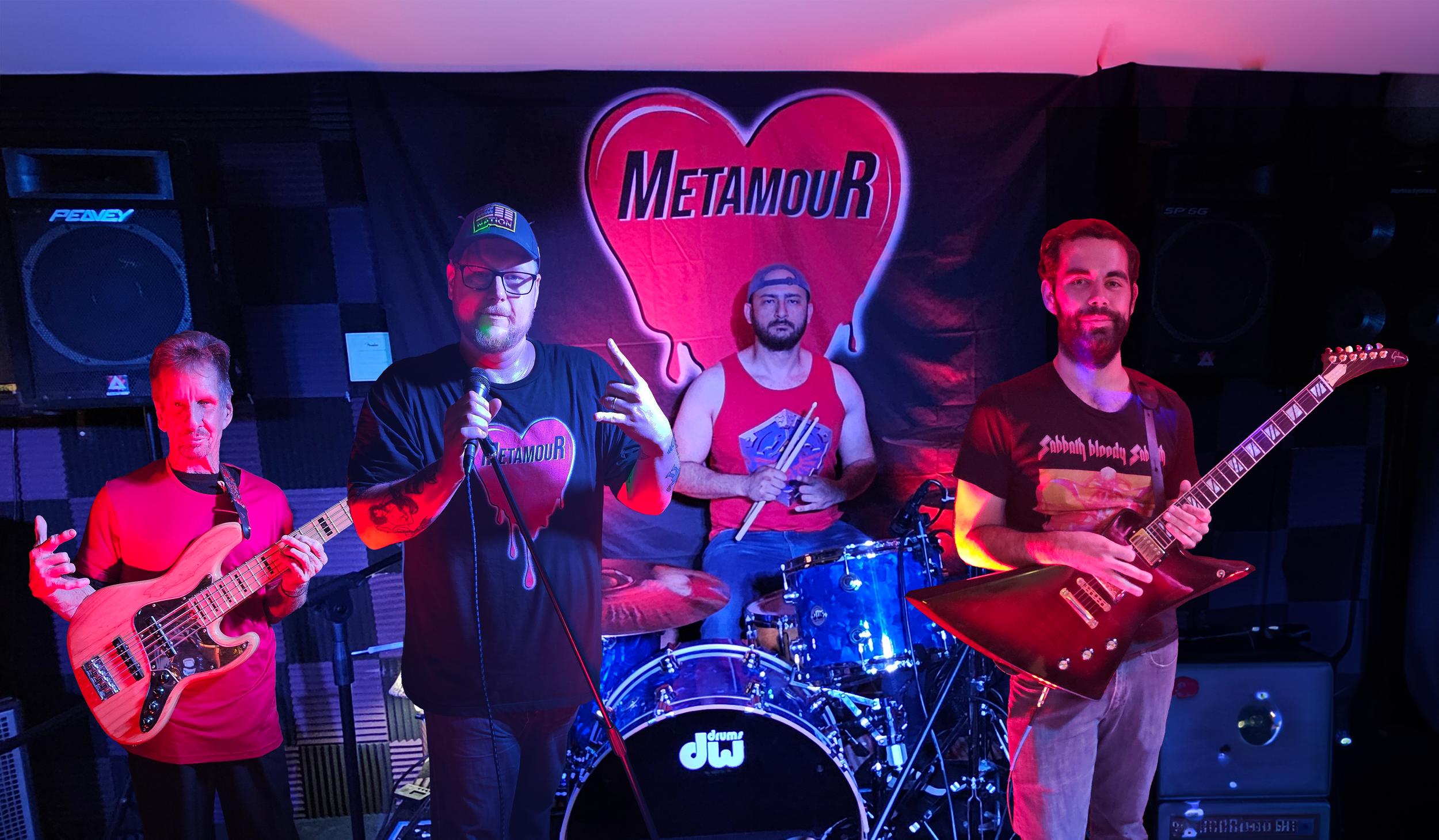 Four musicians pose in a band rehearsal space. The bassist is on the left holding a wooden bass guitar. The vocalist in the center wears a cap and holds a microphone. The drummer sits behind a DW drum kit with drumsticks. The guitarist on the right holds an electric guitar with an angular shape. A banner with the word 'Metamour' and a heart graphic is in the background.