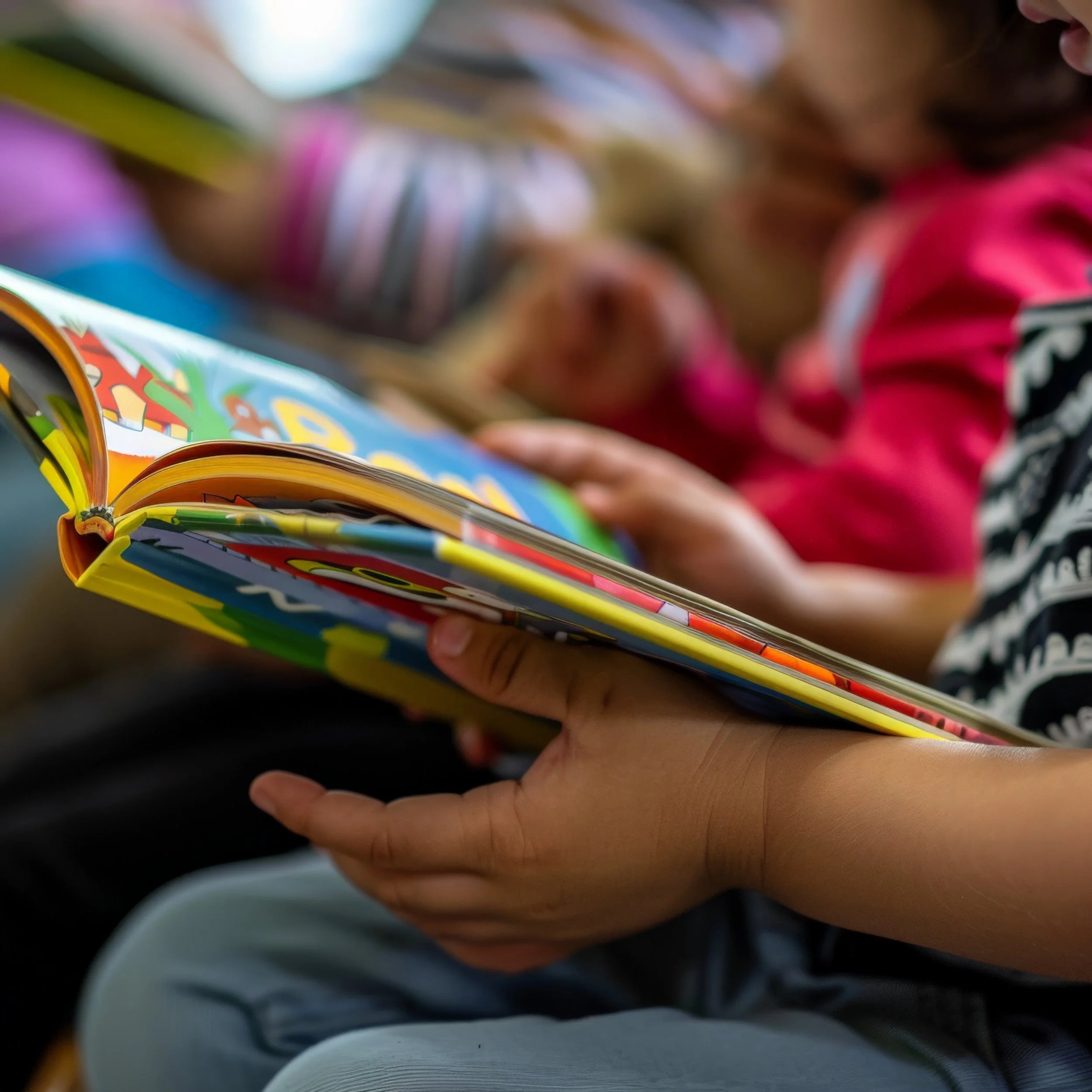 An image of a small child holding a book, perhaps reading with their grown-up!