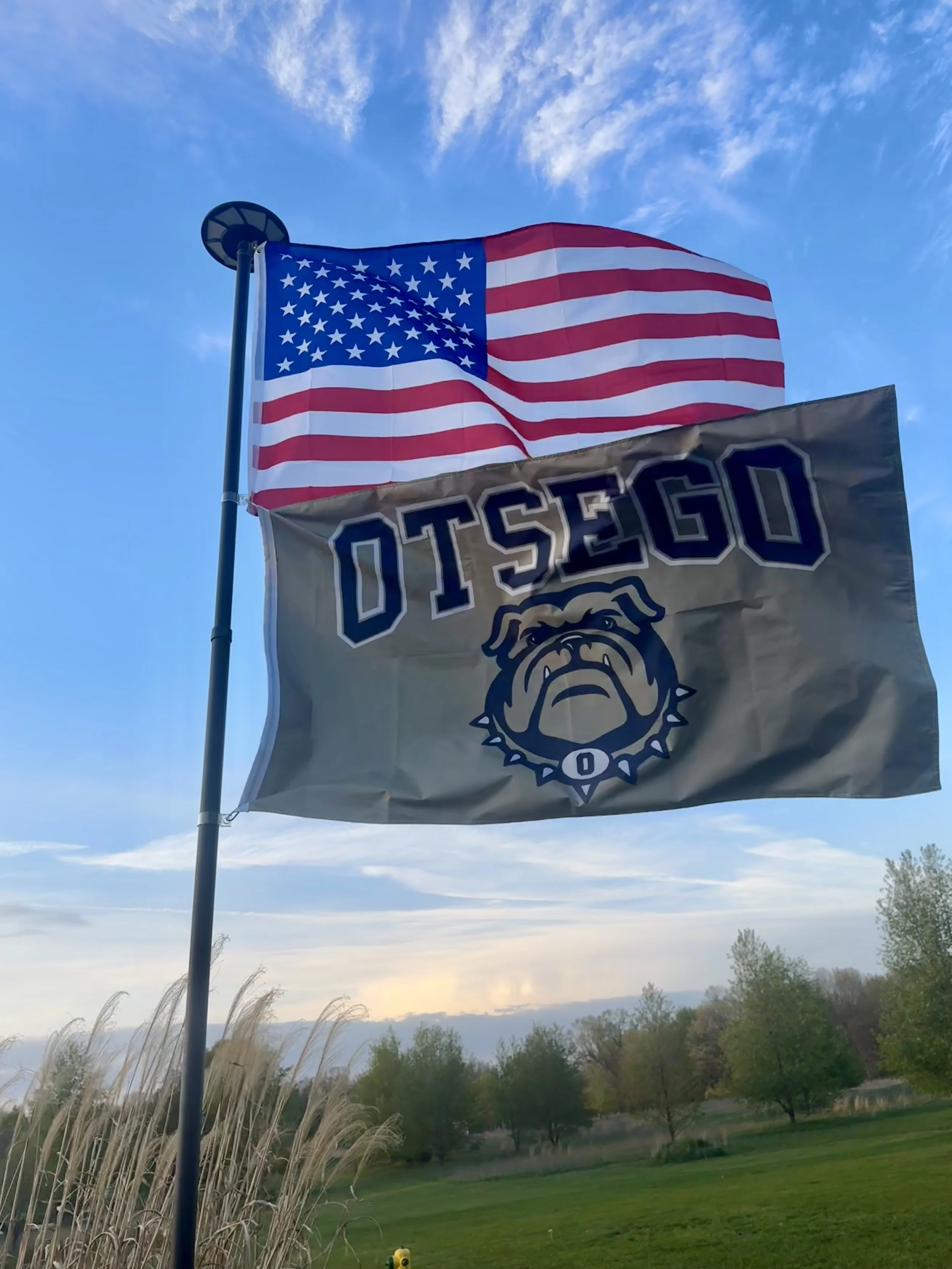 US Flag and Otsego Bulldogs flag on a flag pole