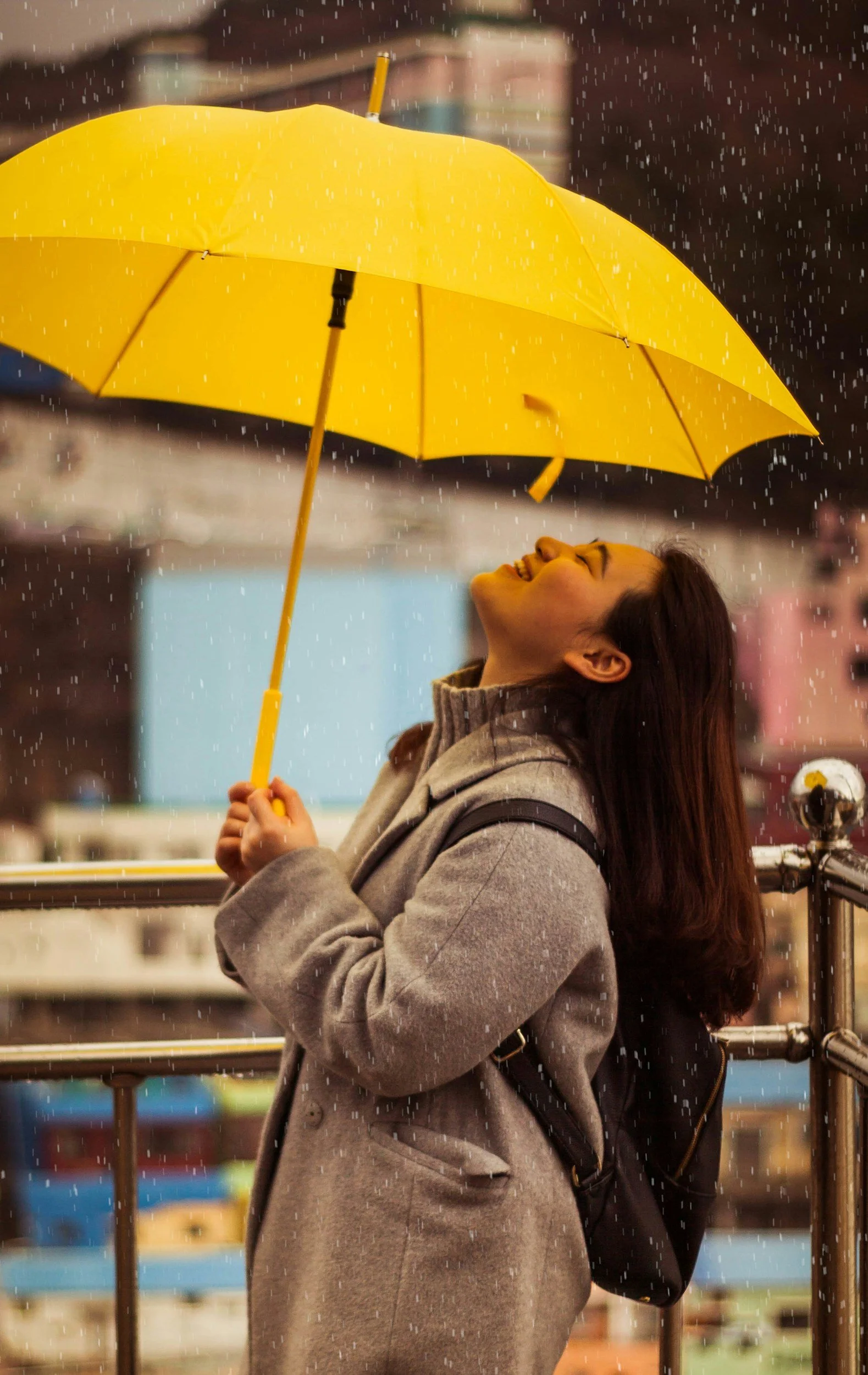 An Asian American woman holding umbrella smiling as therapy for ADHD in NYC brought greater joy