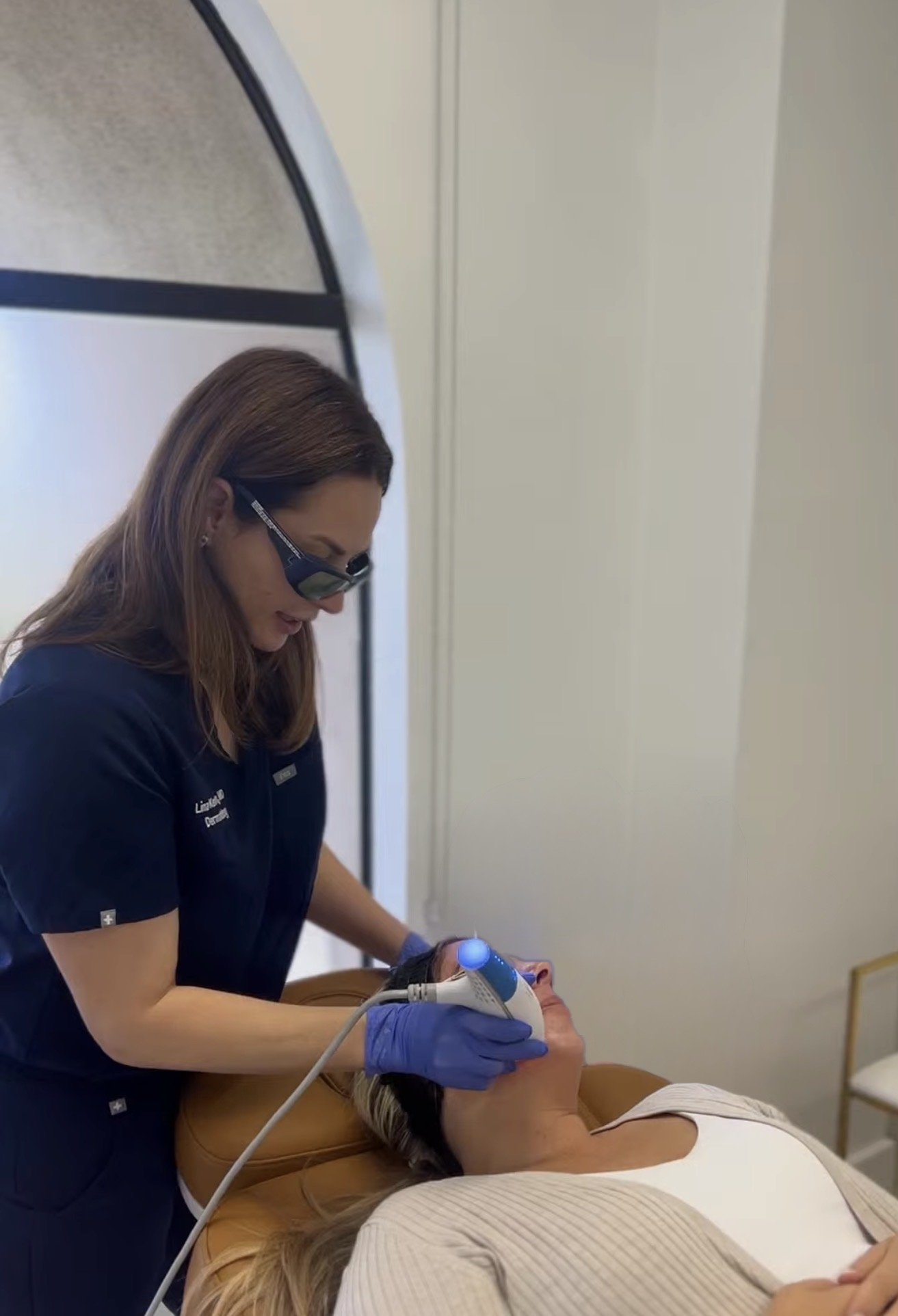 Dr. Lina Kennedy in protective eyewear guiding the Clear + Brilliant handpiece across a patient's face