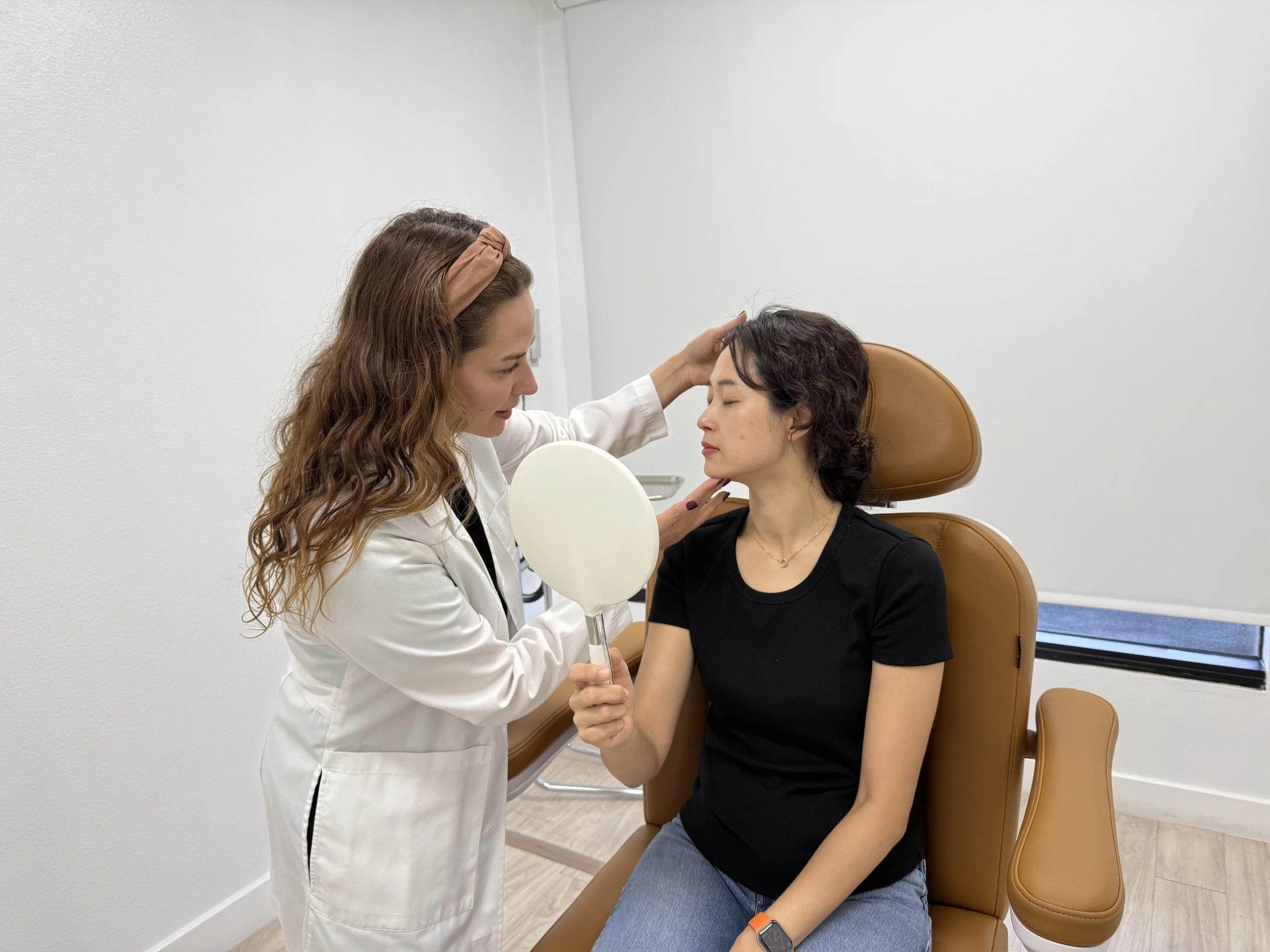 Dr. Lina Kennedy, board-certified dermatologist, examining a patient's facial skin during a melasma consultation