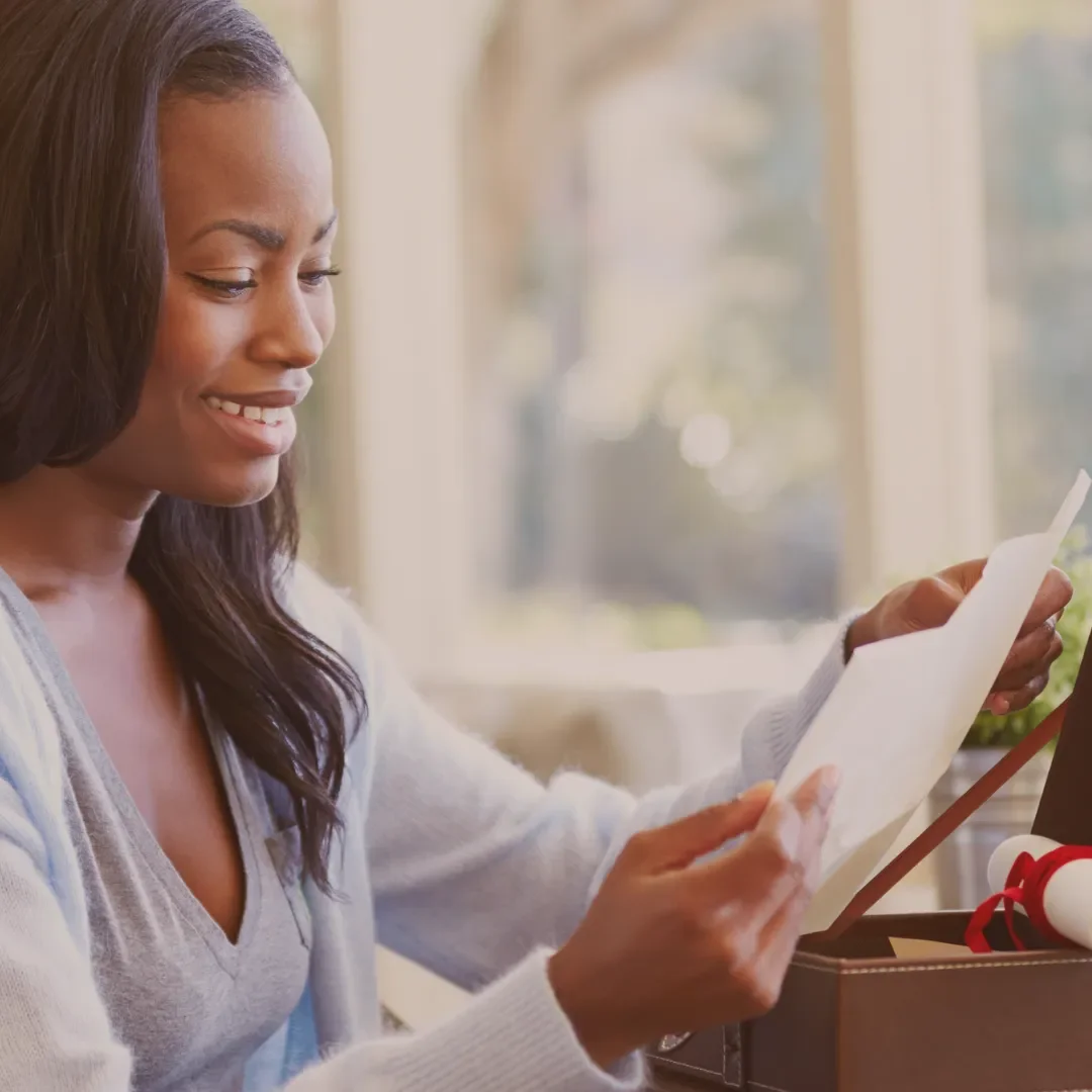 Woman smiling as she reads a letter, reflecting the reassurance of receiving personalised tribute suggestions.