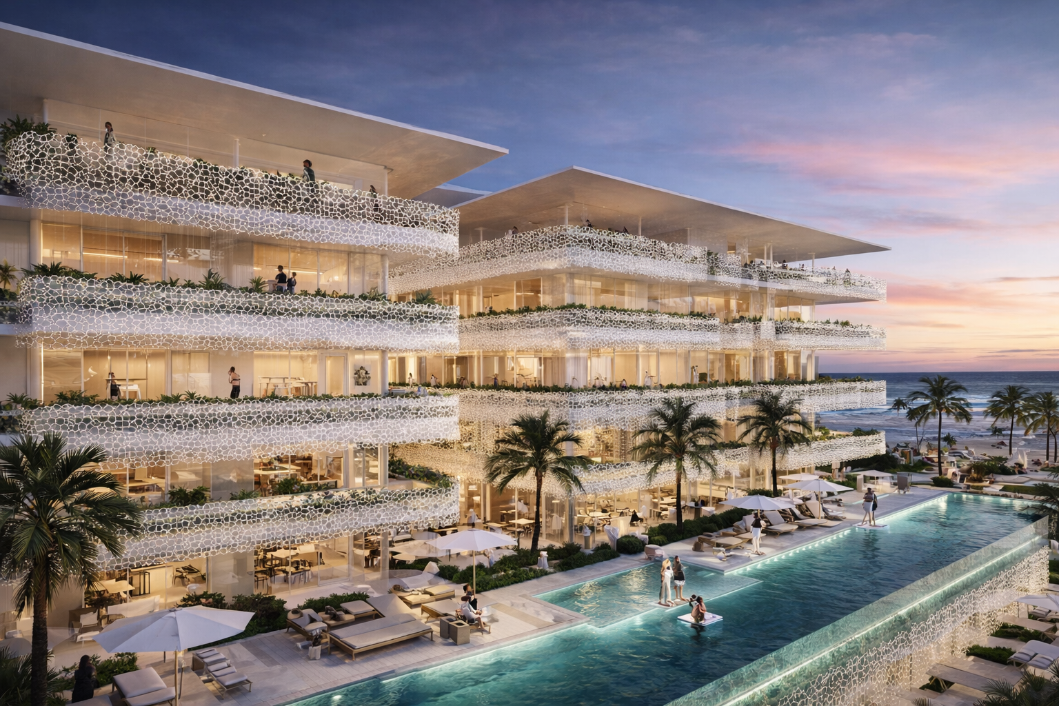 Luxury beachfront hotel with glass balconies, illuminated pool, palm trees, and ocean in the background at sunset.