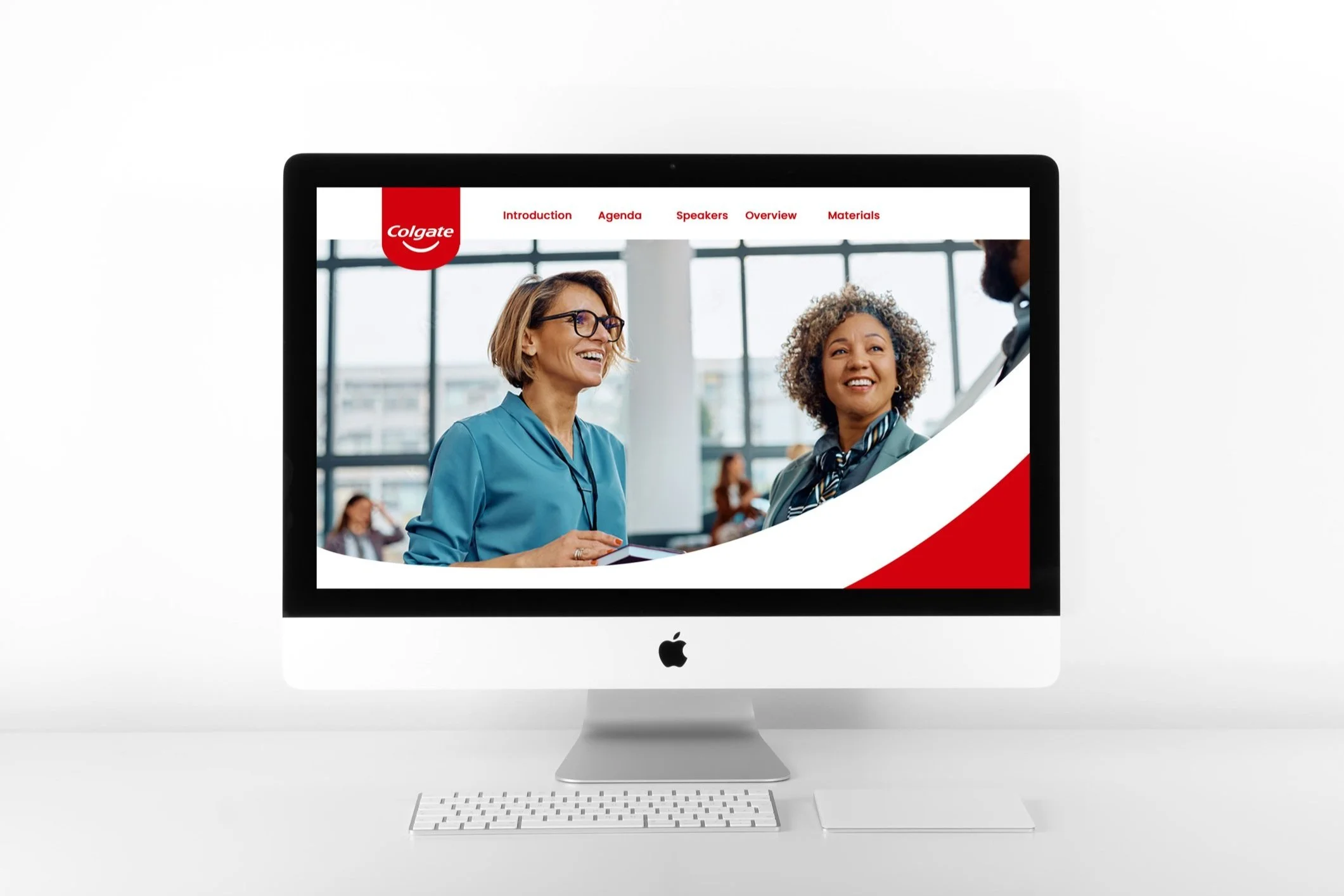 iMac displaying a Colgate webpage with two smiling people, featuring navigation tabs like Introduction and Agenda.