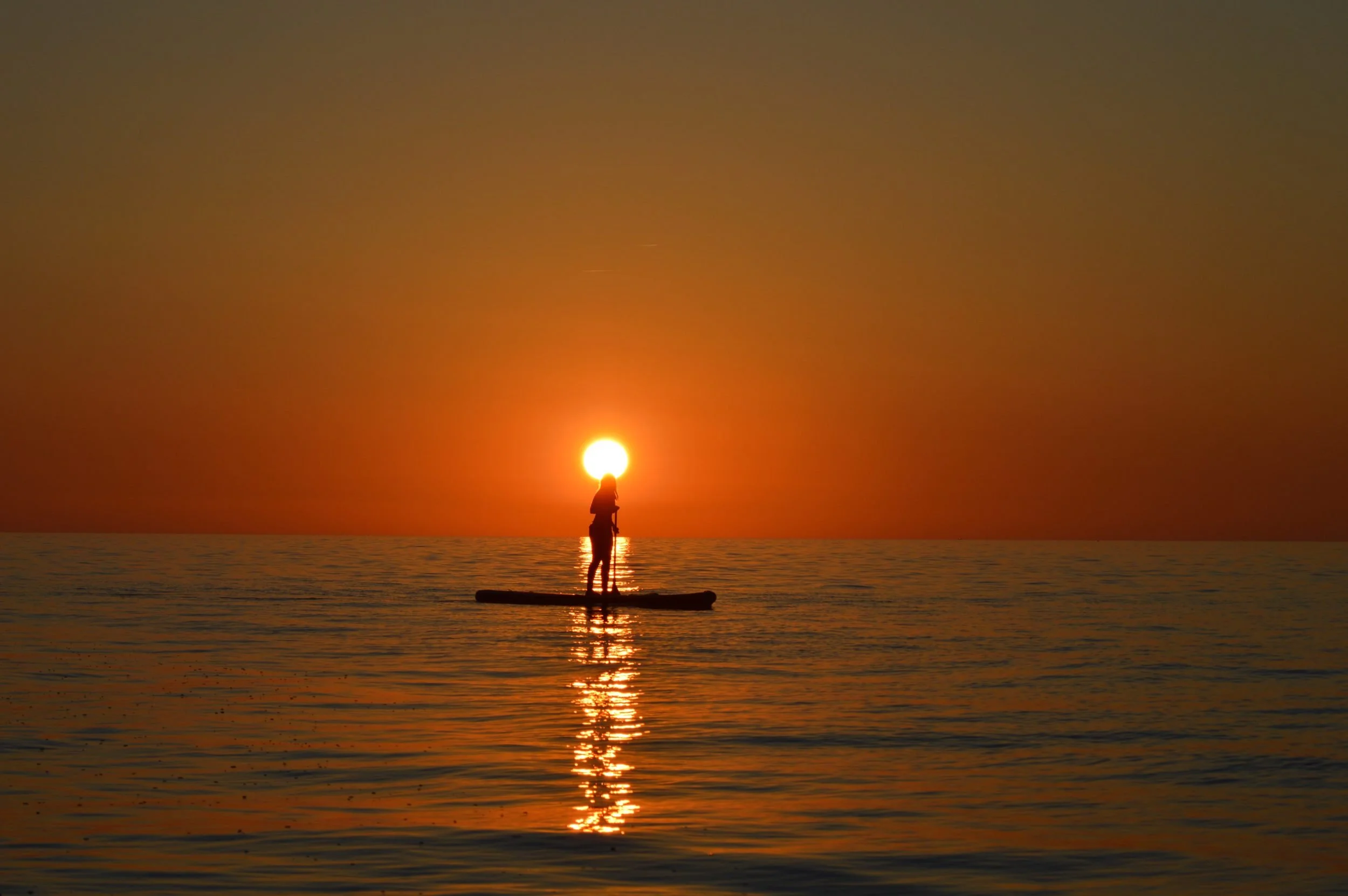 Paddleboarder silhouette setting sun