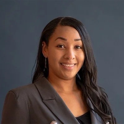 Dr. Ginavra Gibson, counselor, supervisor, consultant, and trainer. Woman with long dark hair smiling in front of a gray background.