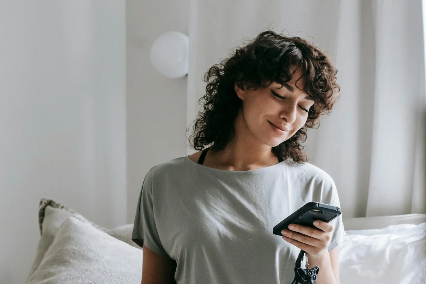 Jeune femme souriante utilisant un téléphone portable à la maison