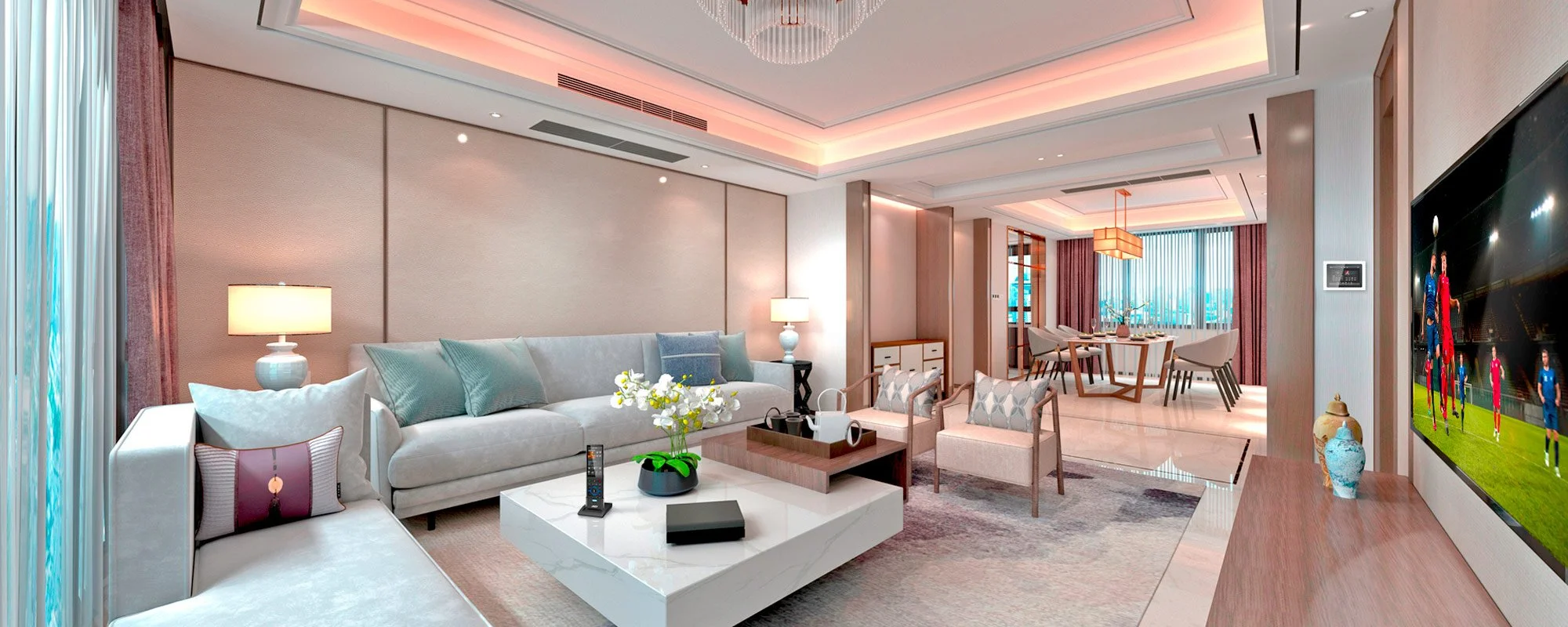 Modern living room with beige decor, sectional sofa, flat-screen TV showing soccer, coffee table with decor, dining area in background, soft lighting.