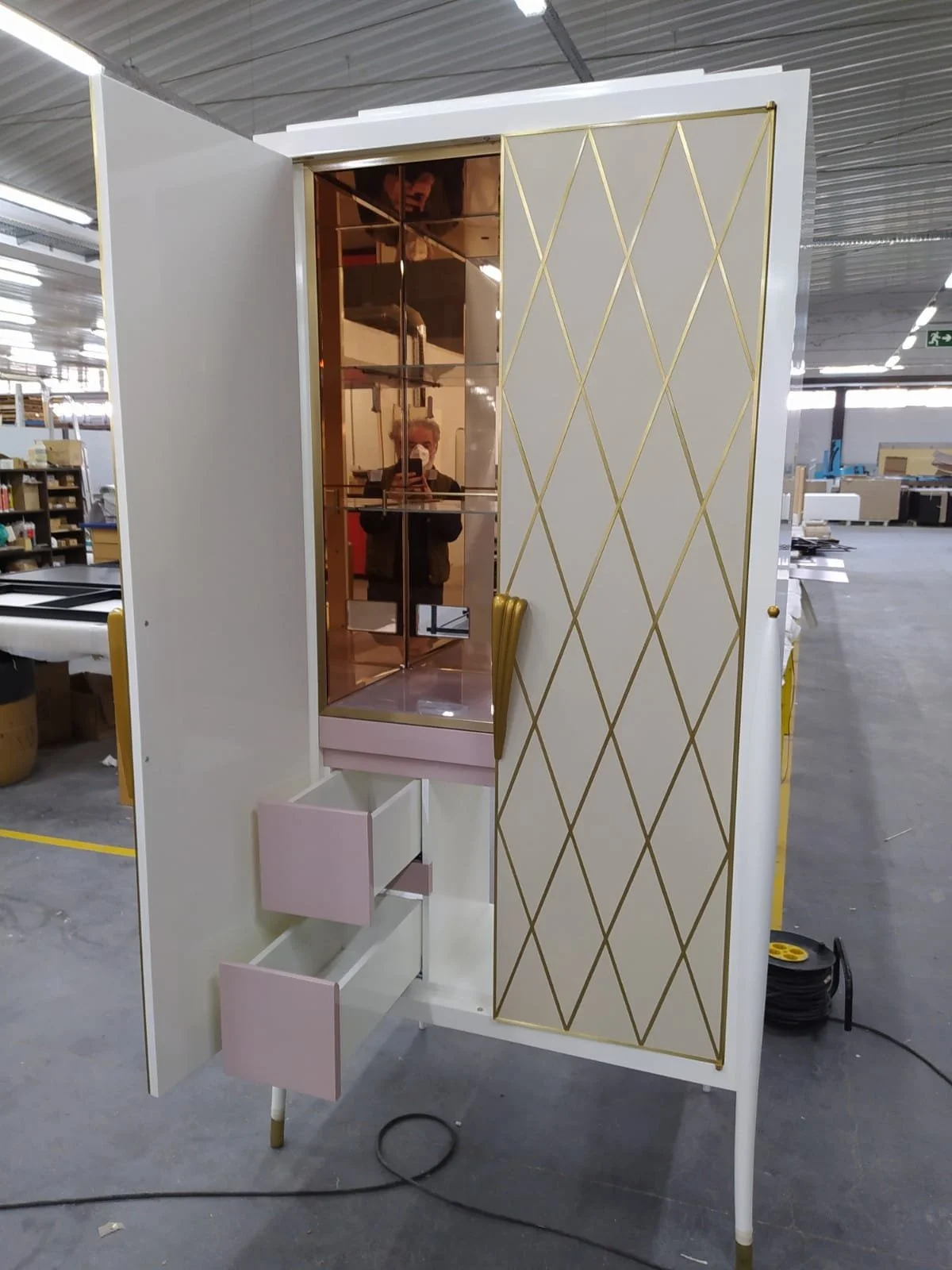 Une armoire stylée avec miroir, tiroirs roses et design doré, dans une usine.