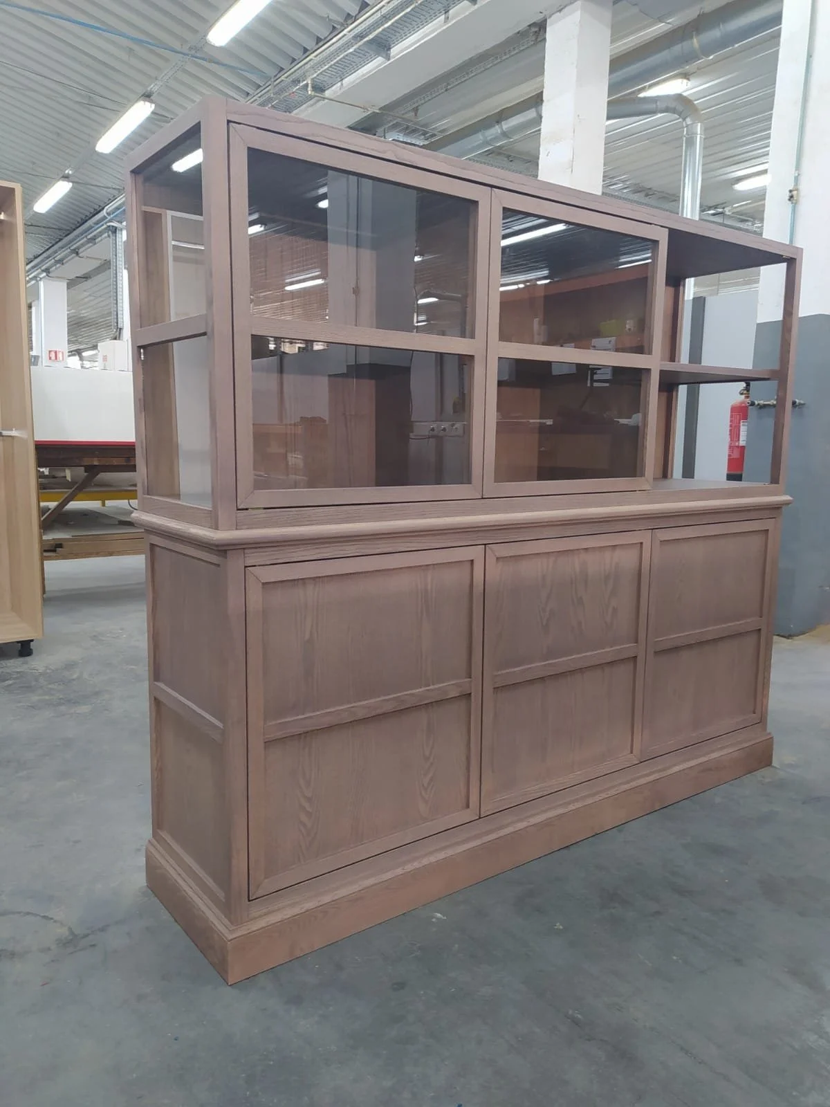 Une vitrine en bois avec parties en verre dans un atelier de menuiserie.