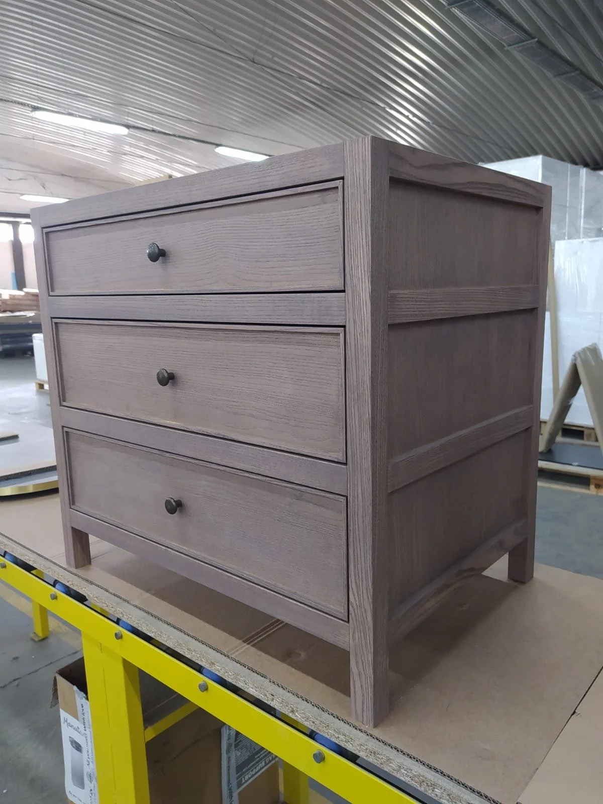 Un meuble en bois avec trois tiroirs dans un atelier de fabrication.