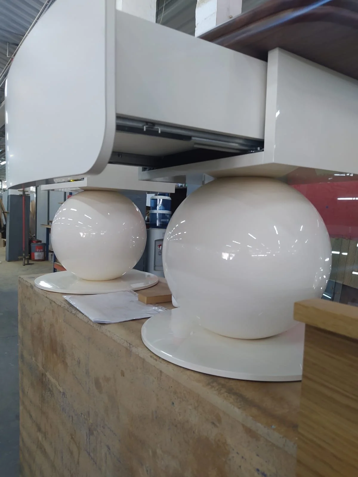 Deux lampes suspendues modernes avec des globes blancs brillants placés sur un comptoir en bois dans un atelier.