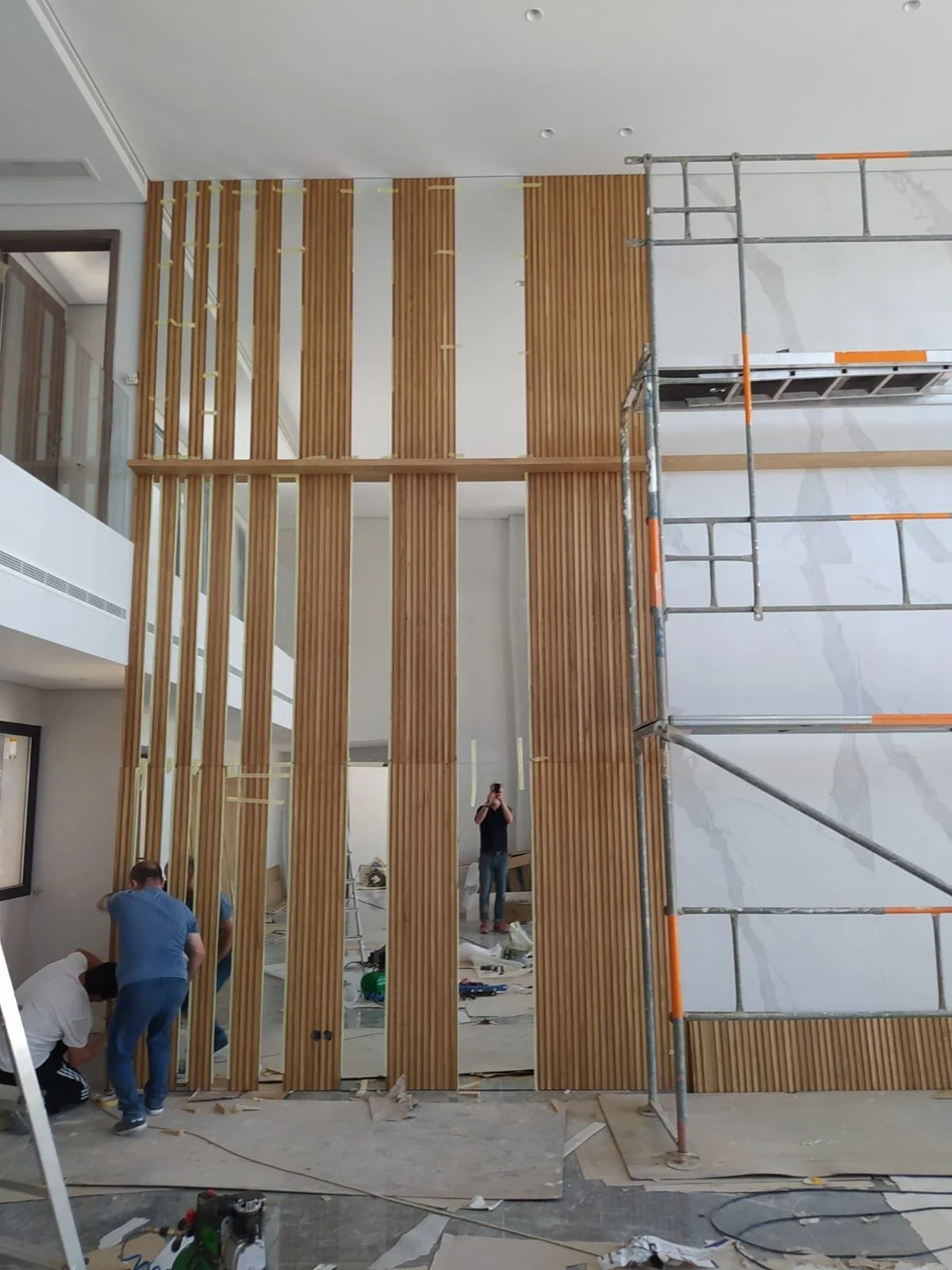 Travaux de construction ou de rénovation intérieure avec des travailleurs installant des panneaux en bois vertical sur un mur