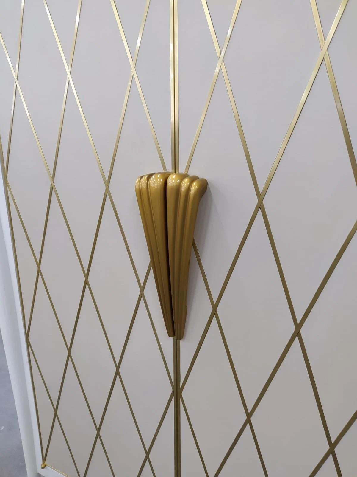 Une porte avec un motif géométrique en or et blanc, avec une poignée décorative en or.