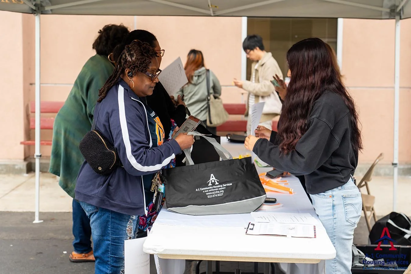 woman-receiving-information-and-an-a-1-community-housing-services-black-tote-bag-with-white-lettering.jpg
