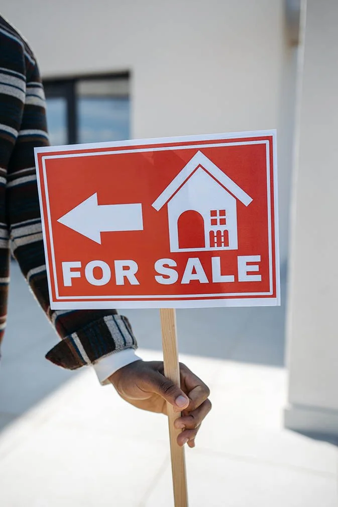 Person holding a sign that says home for sale.