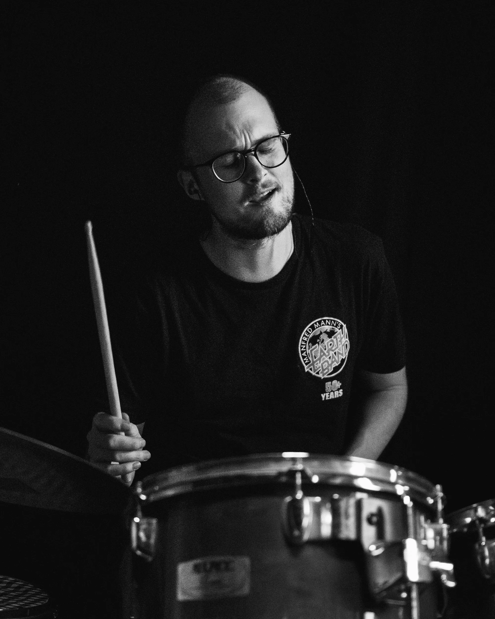 Expressive black and white rehearsal portrait of drummer in studio setting, part of the Bucky Krück atmospheric portrait series.