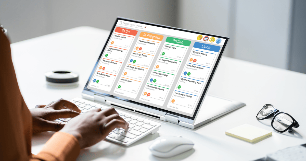 An Elite Remote Partner working on a laptop with project management software displaying tasks in 'To Do', 'In Progress', 'Testing', and 'Done' columns.