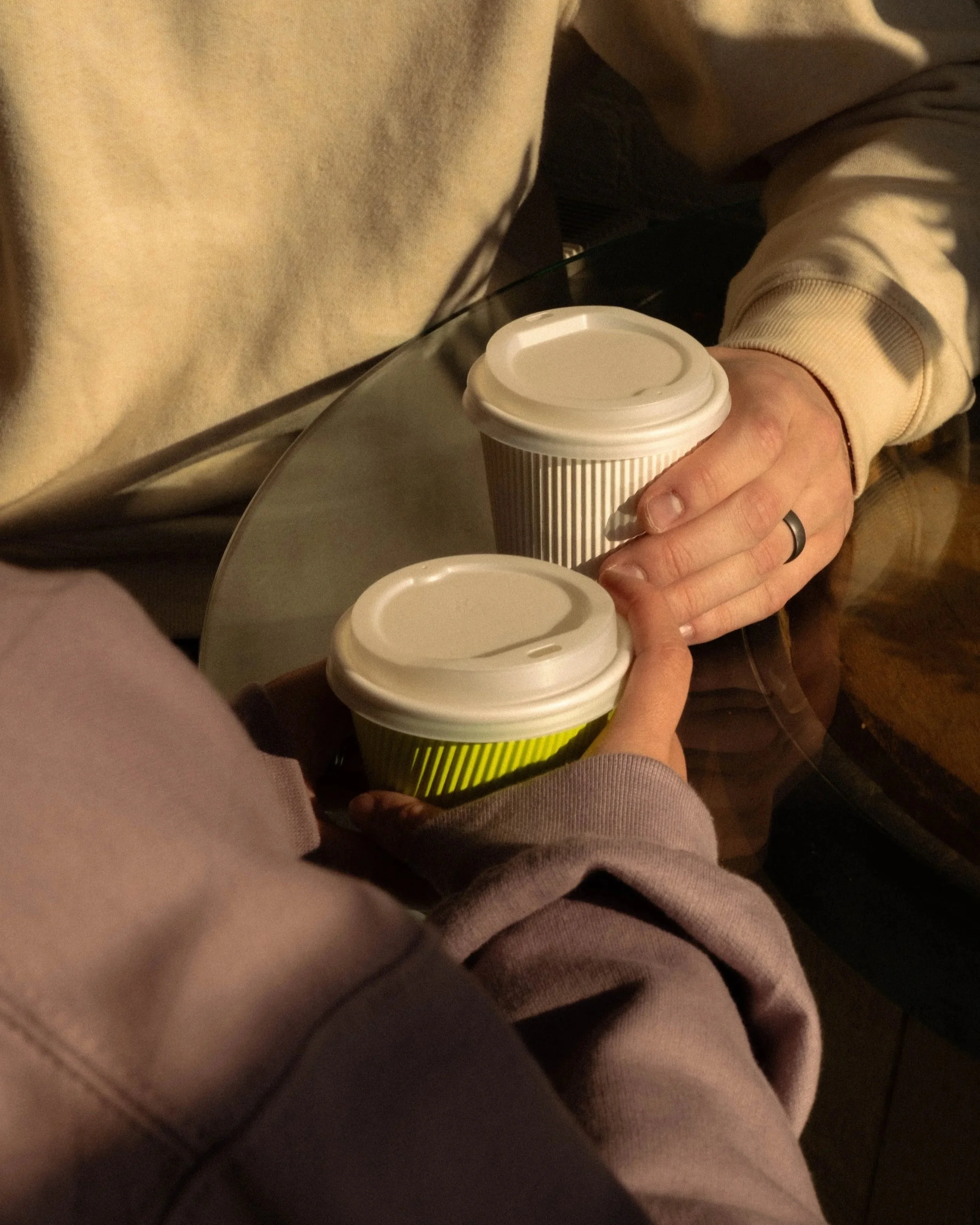 a couple sitting down at a cafe with lattes to go