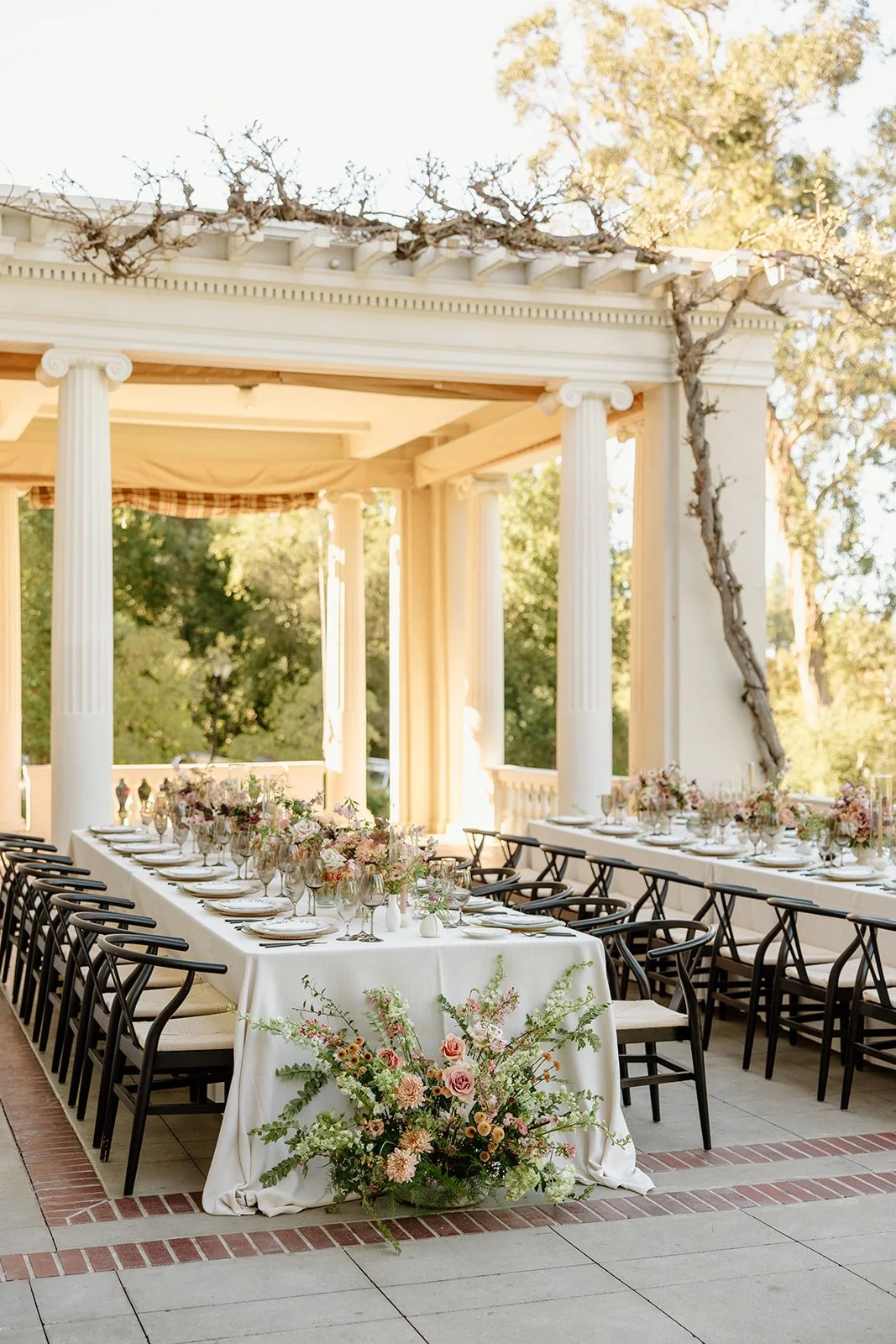 Elegant outdoor wedding reception at Villa Montalvo in Saratoga, California, with long tables draped in white linen and decorated with garden-style floral arrangements of roses, dahlias, and seasonal blooms in soft pinks and whites.