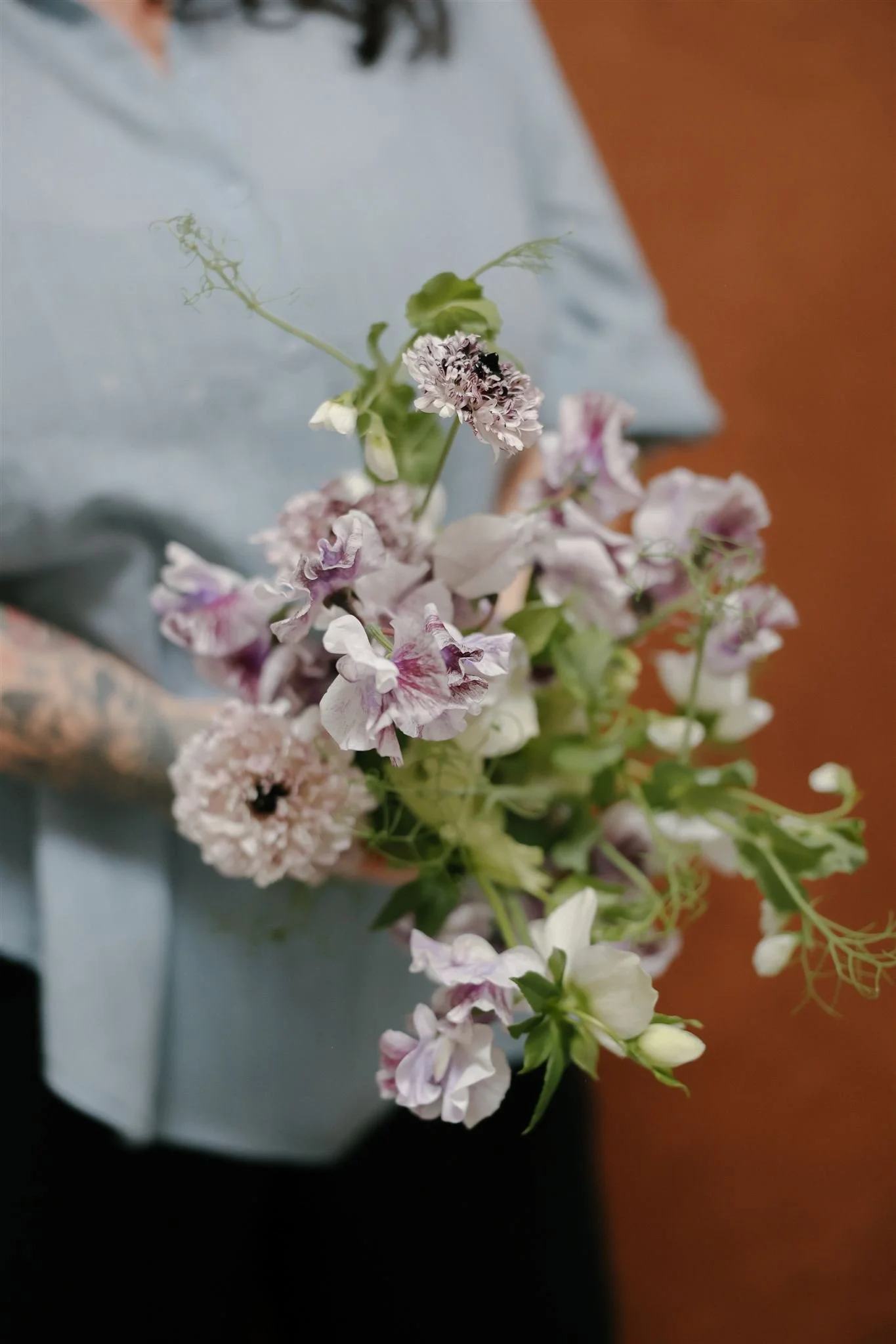 Hand-tied bridal bouquet with sweet peas, ranunculus, and white hellebore, designed by Petal + Salt Floral