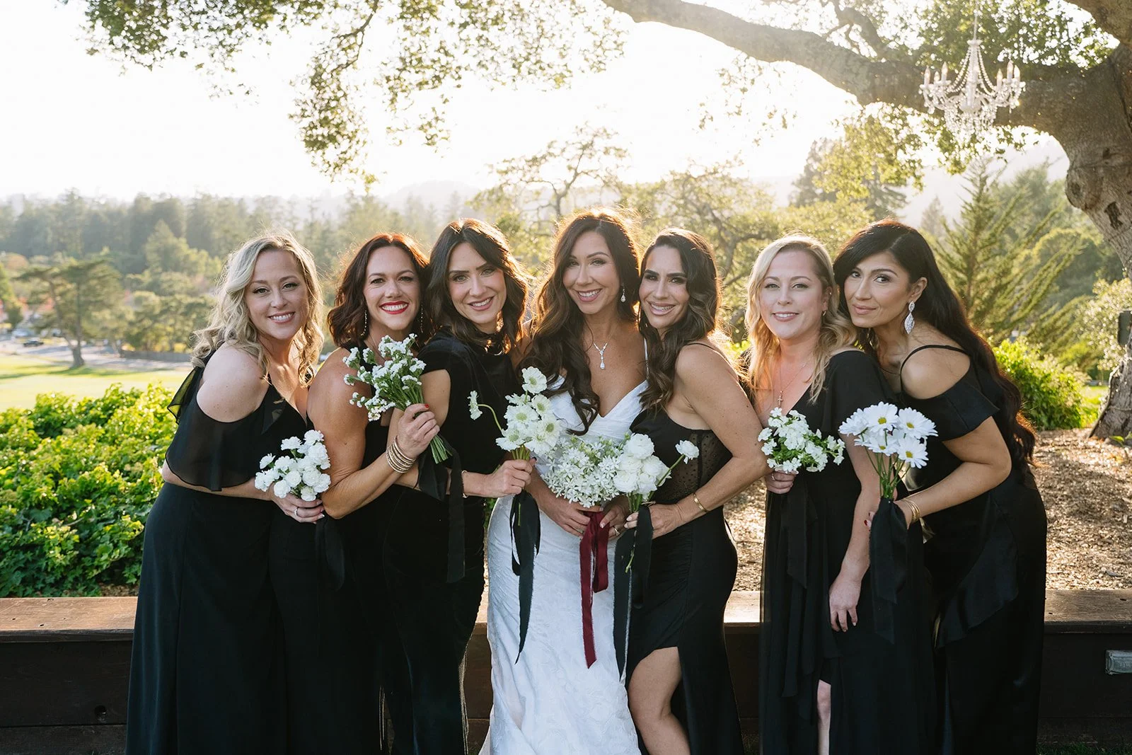 Bride and bridesmaids holding matching white bouquets at Hollins House Santa Cruz in dappled sunlight, wedding party florals by Petal + Salt
