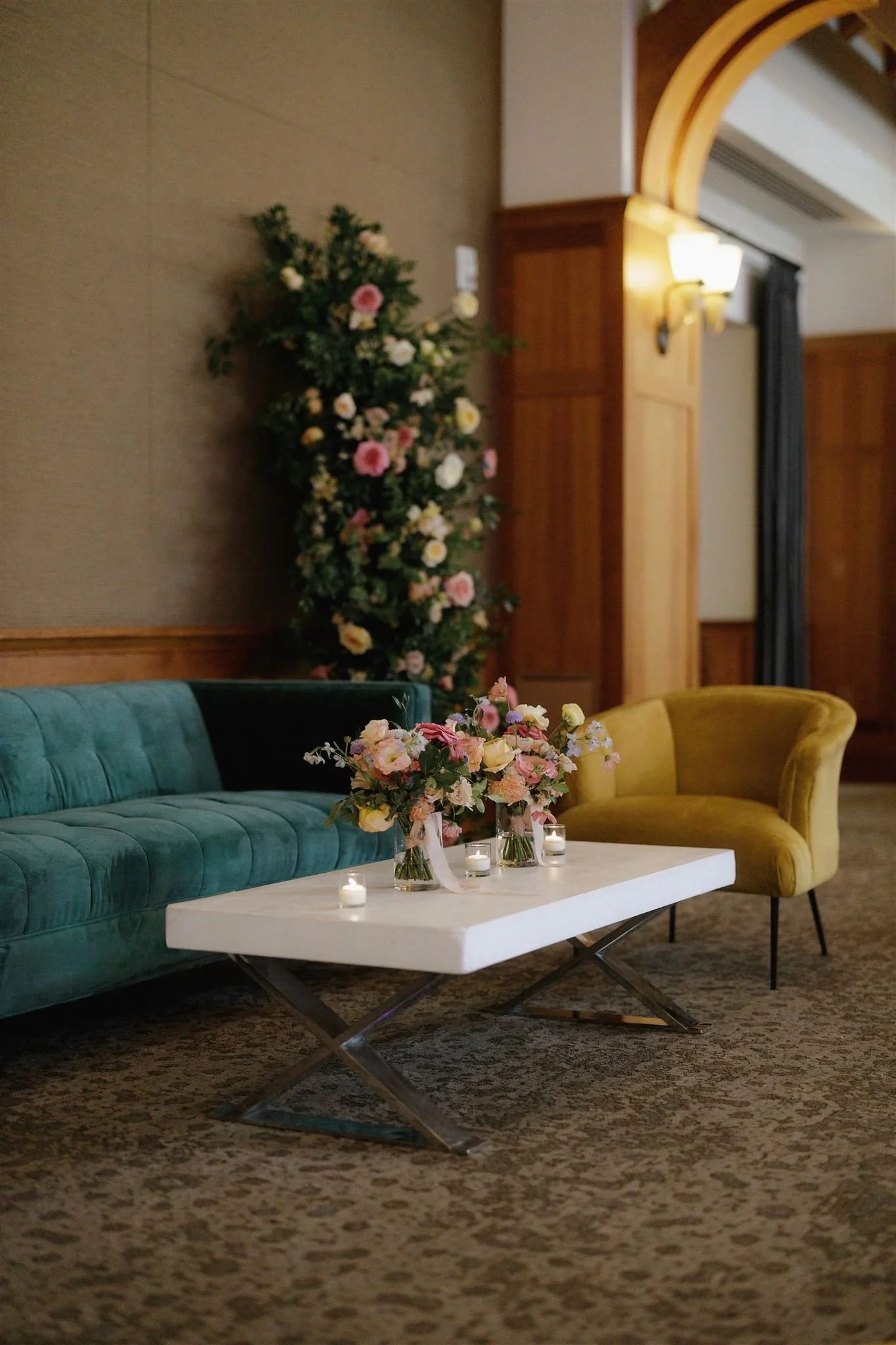 Wedding flowers at Sharon Heights Country Club in Menlo Park, California, featuring a lush floral installation of roses, ranunculus, and greenery paired with bridesmaid's bouquets on cocktail tables.