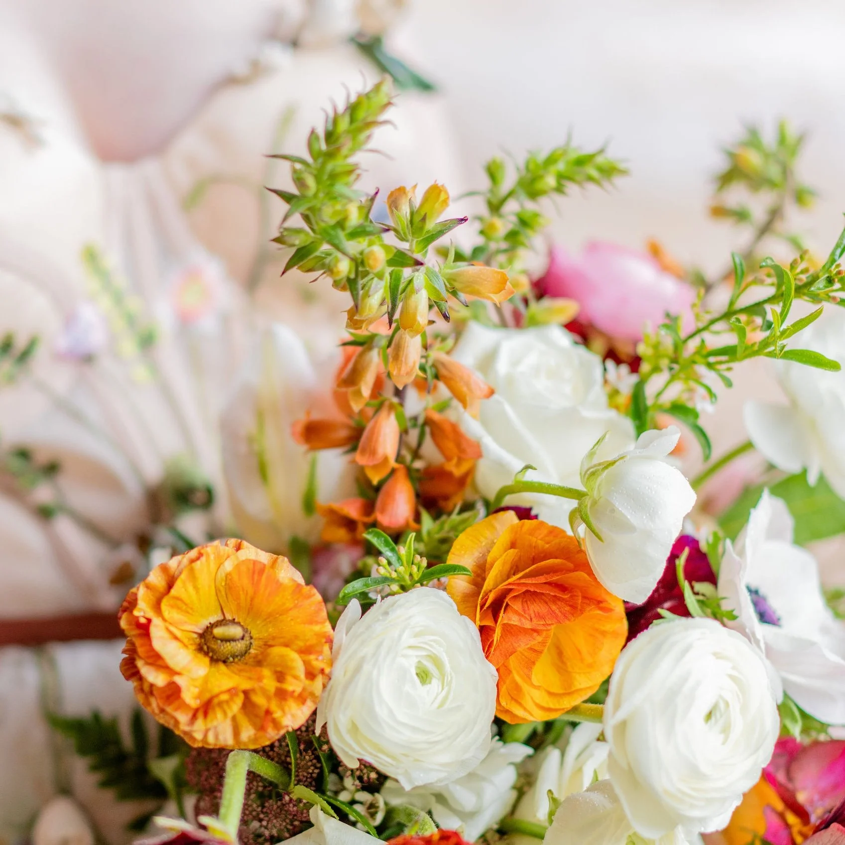 Close-up of a colorful bridal bouquet of various flowers including white ranunculus, orange poppies, and other small, pink, and green flowers. Santa Cruz California wedding. Beach Wedding. 