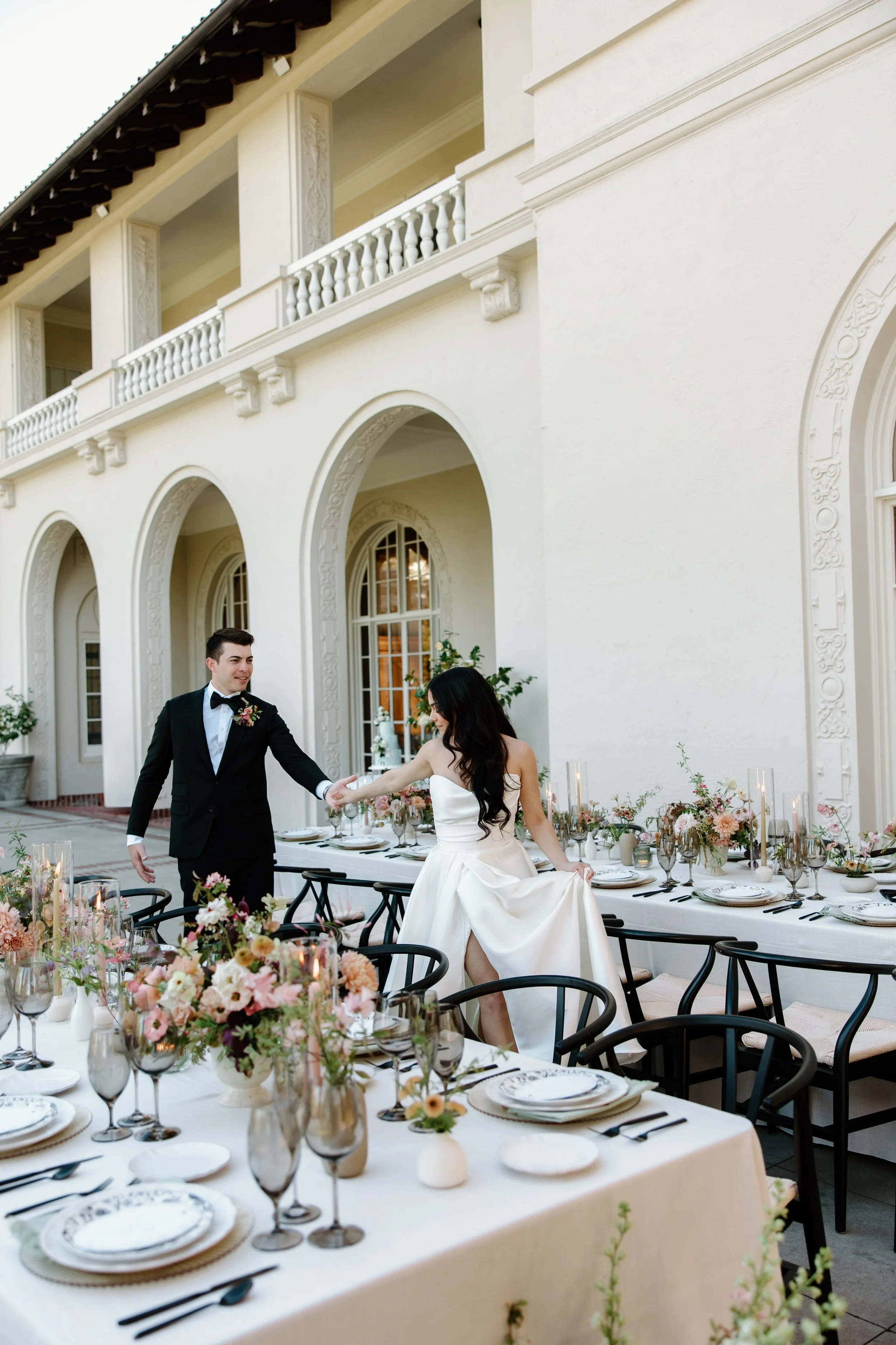 Bride and groom strolling through their wedding reception a floral and candlelit outdoor veranda setup at Villa Montalvo in Saratoga, florals by Petal and Salt Floral