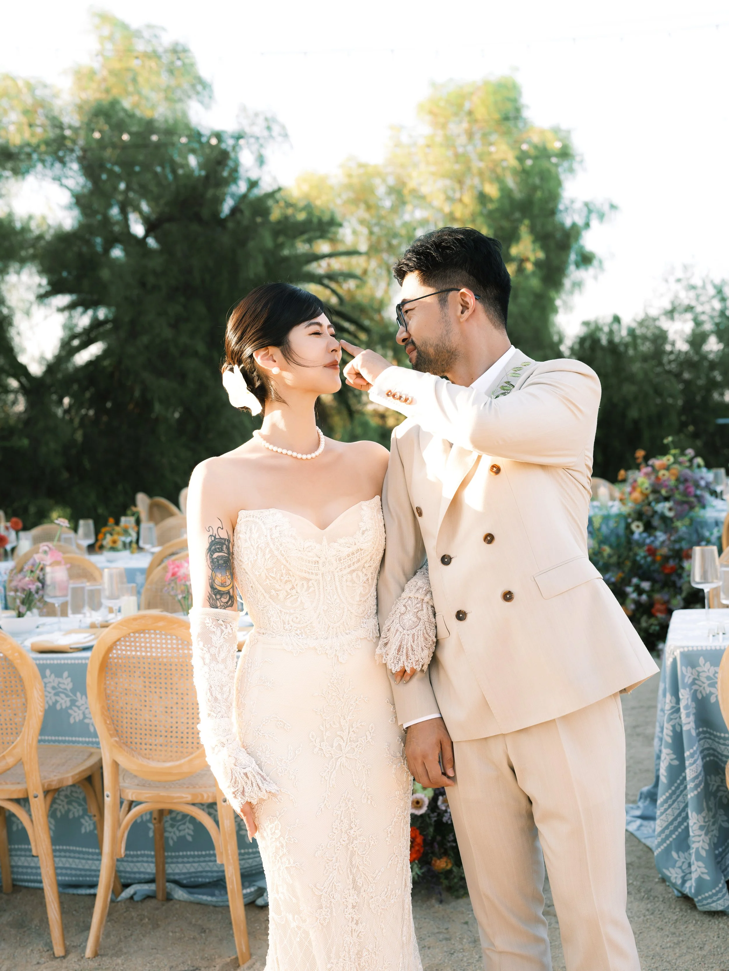 Bride and groom at their outdoor wedding reception at Olive Hill Estate with floral-decorated tables behind them, Bay Area wedding florals by Petal and Salt