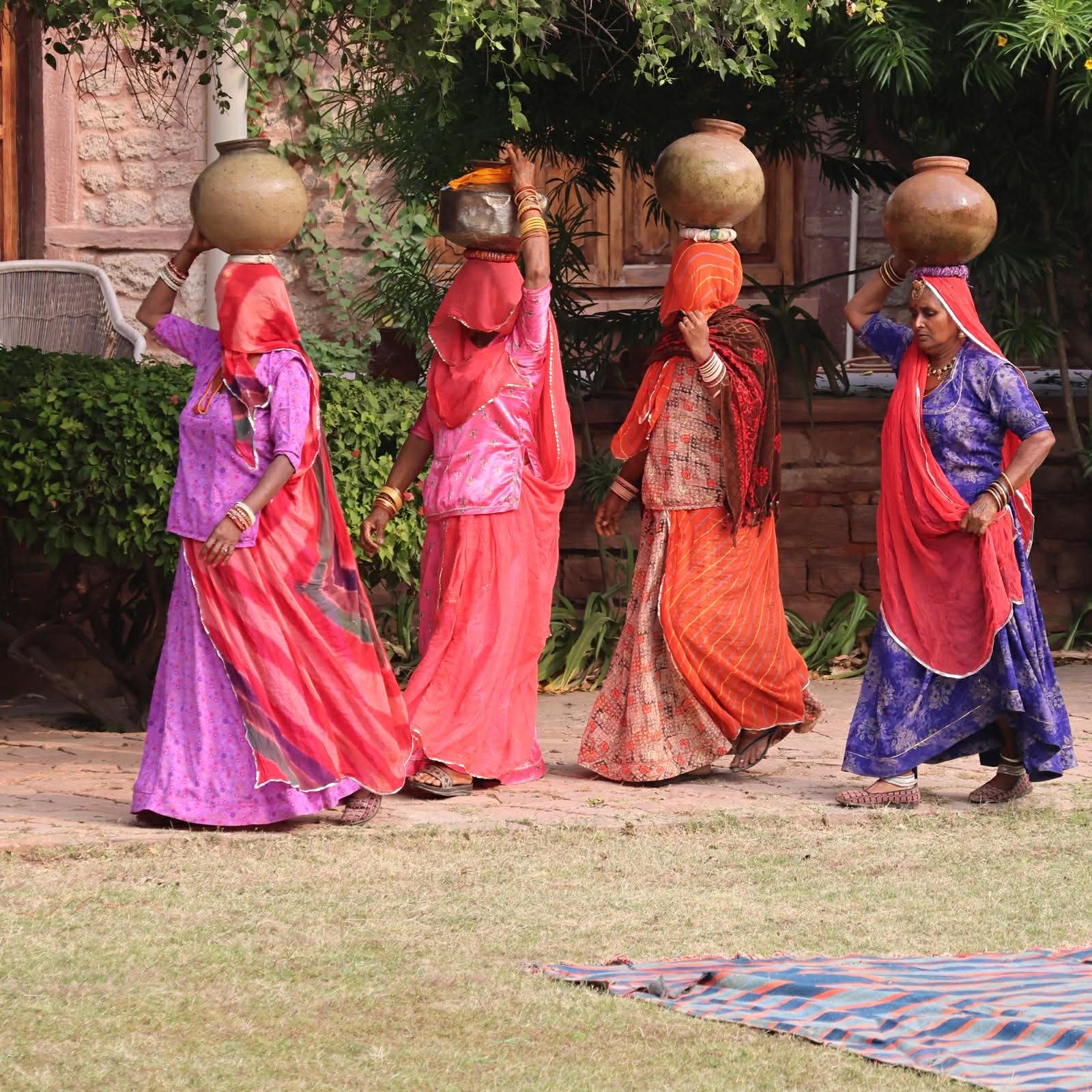 Indian women in saris carrying water vessels