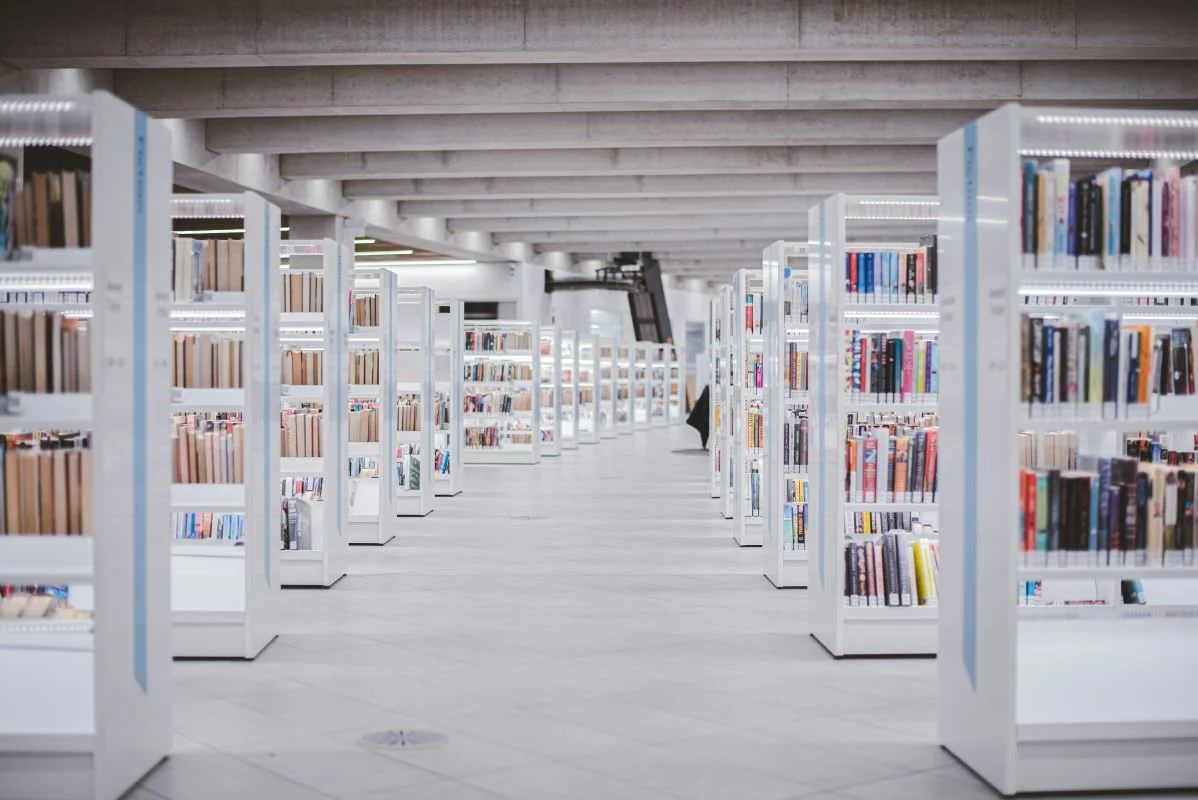 long row of bright shelves of books in a library or archive