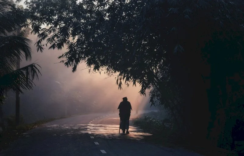 figure walking on a road in shadows and sunlight