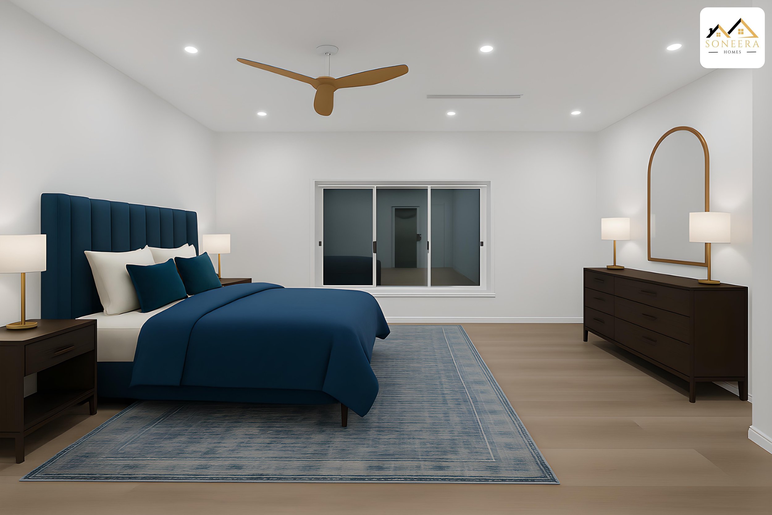 Modern bedroom with a large bed, navy blue bedding, and pillows, two bedside tables with lamps, a wooden dresser with two lamps, a window, a ceiling fan, and a blue area rug on light wood floor.