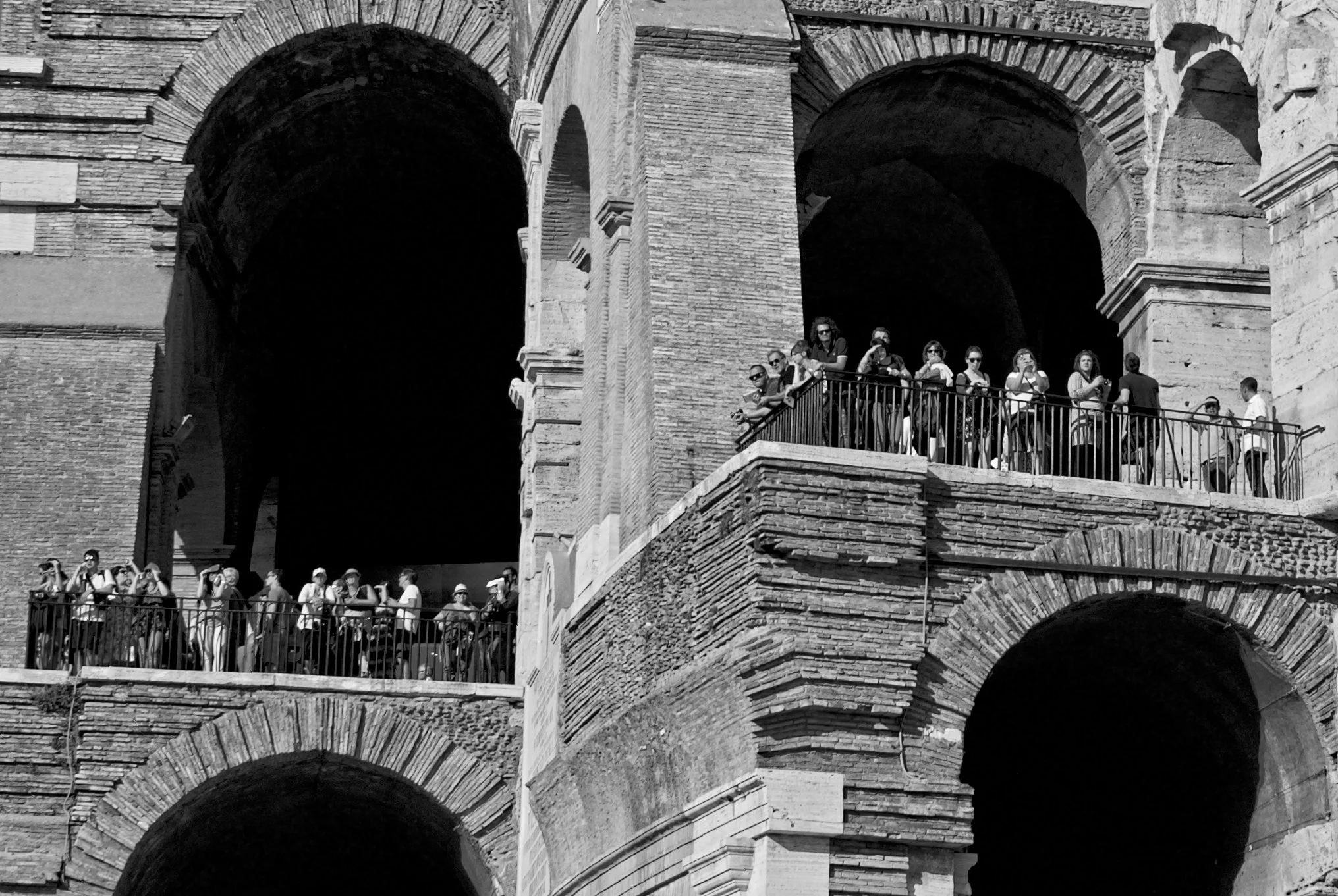 Tourists standing on viewing platforms inside the arches of the Colosseum in Rome, Italy, during daytime.