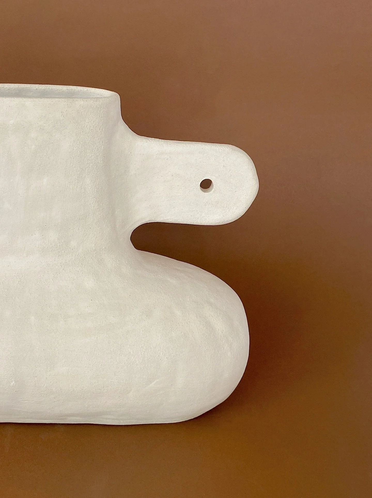This one makes me think of cutting symmetrical shapes out of paper. First folding the paper in half, cutting the shape on one side, and opening it to reveal the mirrored form. I like this especially as the creamy grogged clay even looks a bit like cr