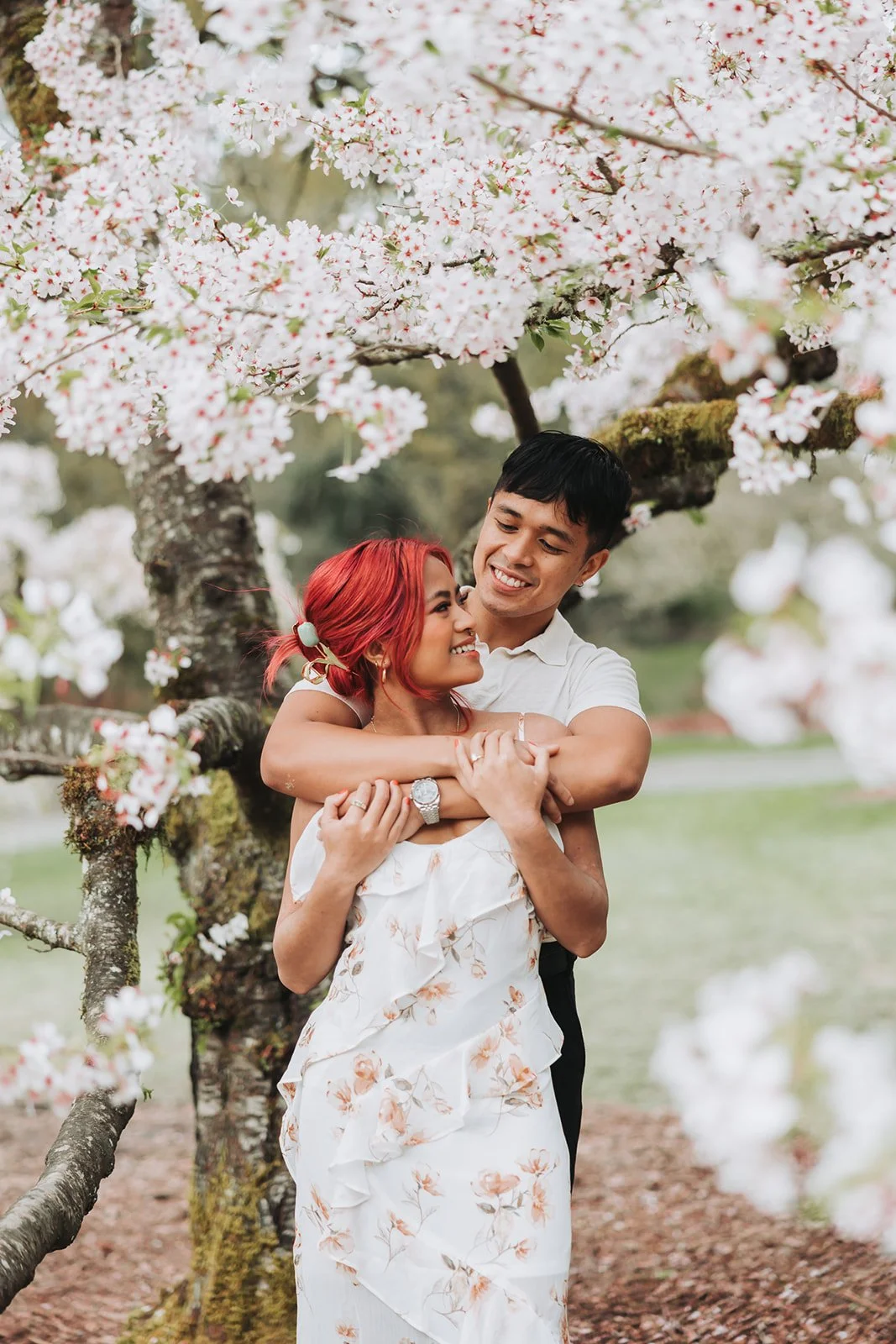 Engaged couple under a cherry blossom tree at Washing Park Arboretum