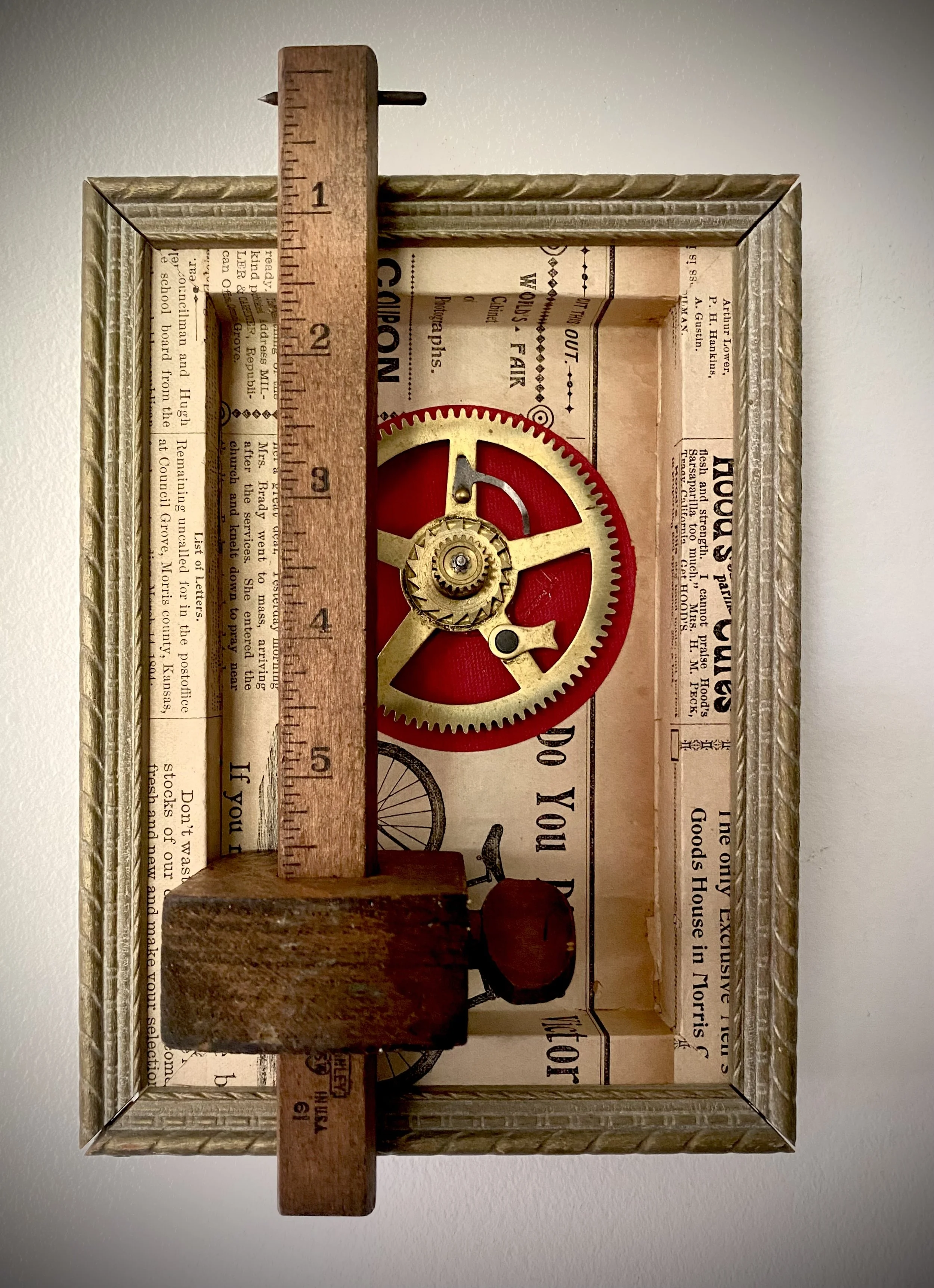 Assemblage artwork featuring a vintage wooden measuring rule positioned over mechanical elements and layered papers.