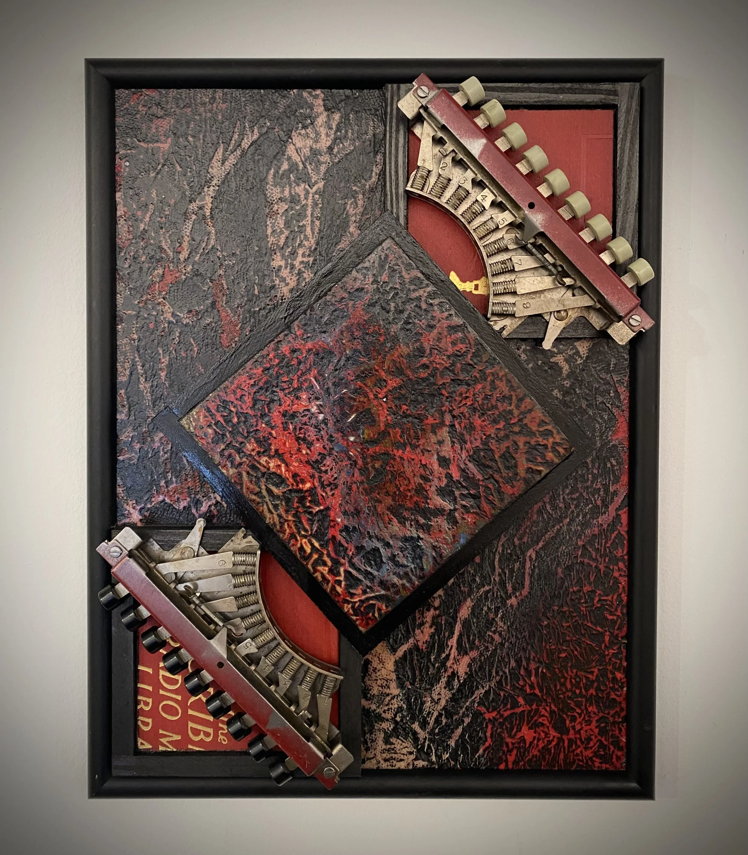 Assemblage artwork featuring vintage typewriter mechanisms against richly textured red and black surfaces.