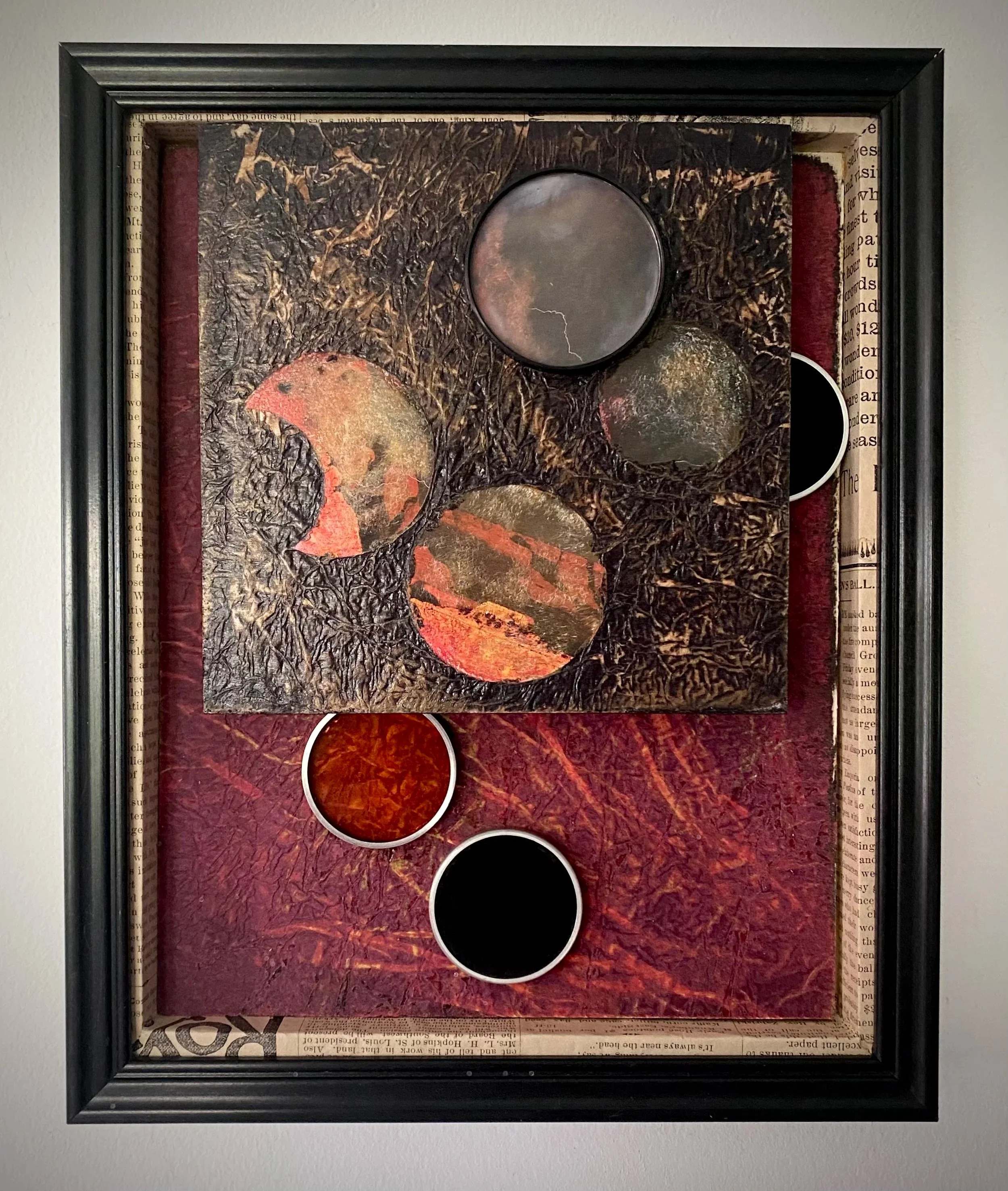 Mixed media assemblage featuring layered circular forms against richly textured black and red surfaces.