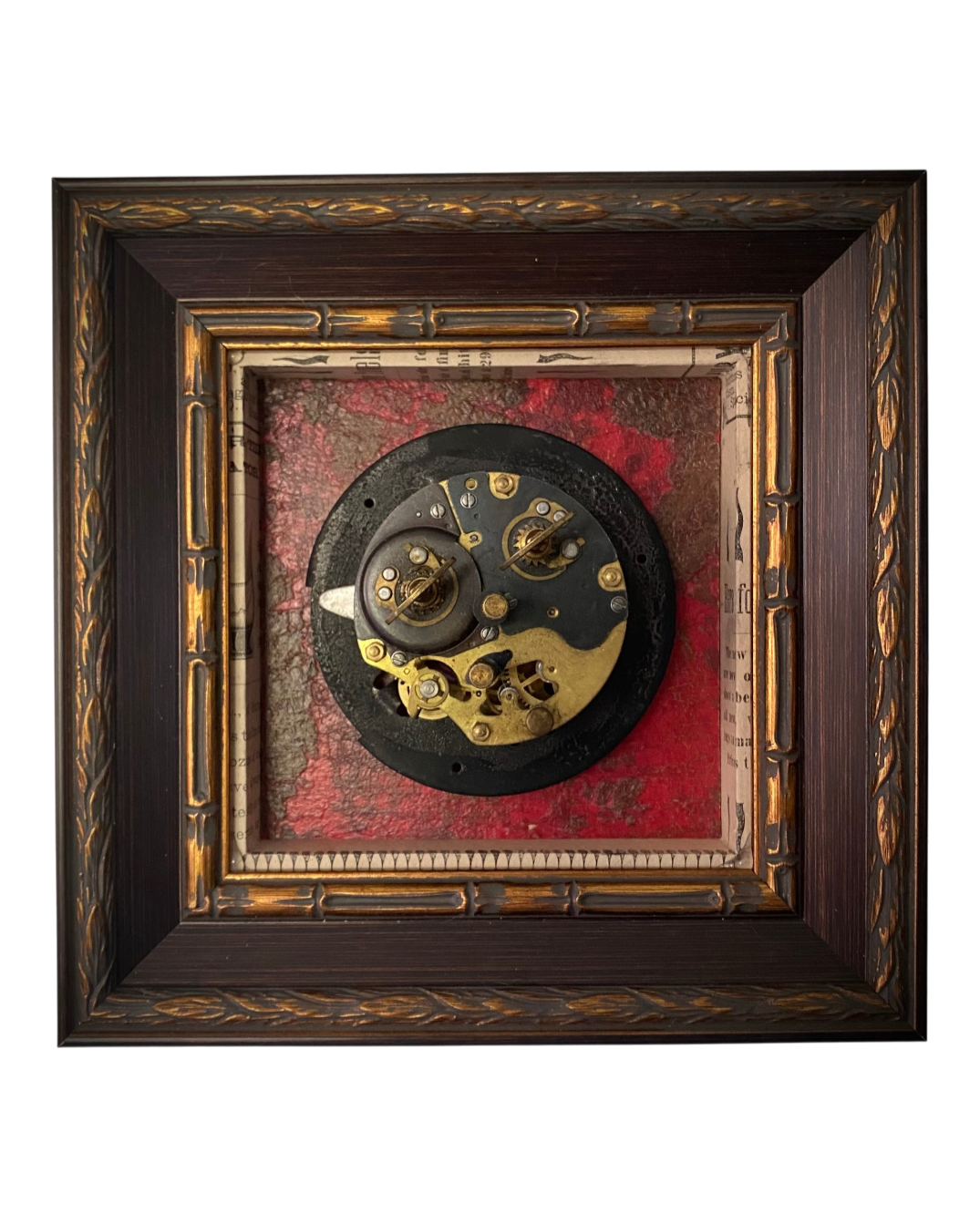 Assemblage artwork featuring a vintage clock movement centered on richly textured red and black surfaces within a shadow box frame.