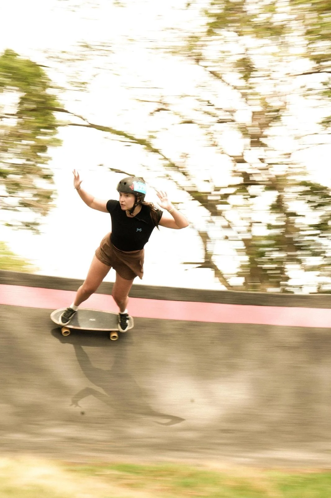 Four women walking on a sandy beach with mountains in the background and a blue sky with some clouds.
