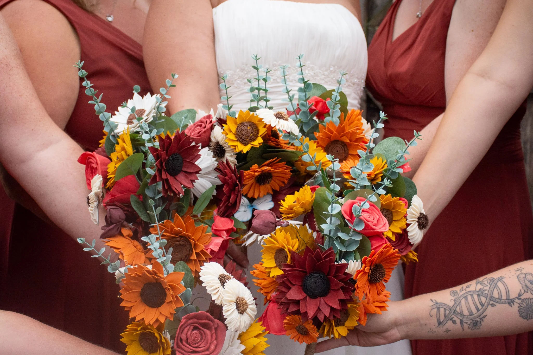 Group of women holding a colorful bouquet of paper flowers at a wedding celebration.