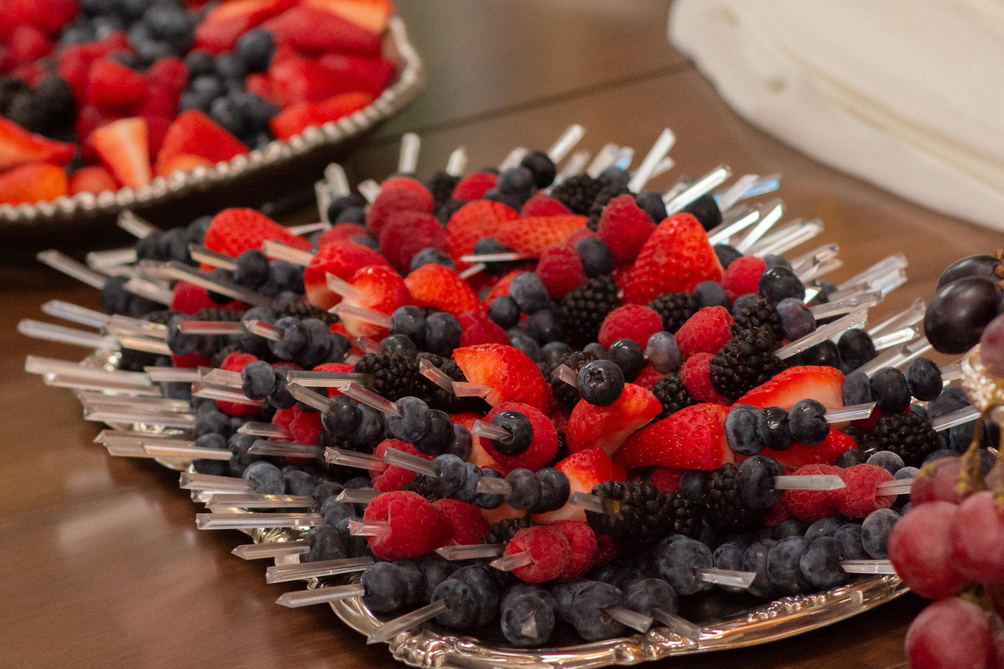 Assorted fresh berries, including strawberries, blueberries, raspberries, and blackberries, arranged on a decorative silver platter for a fruit display.