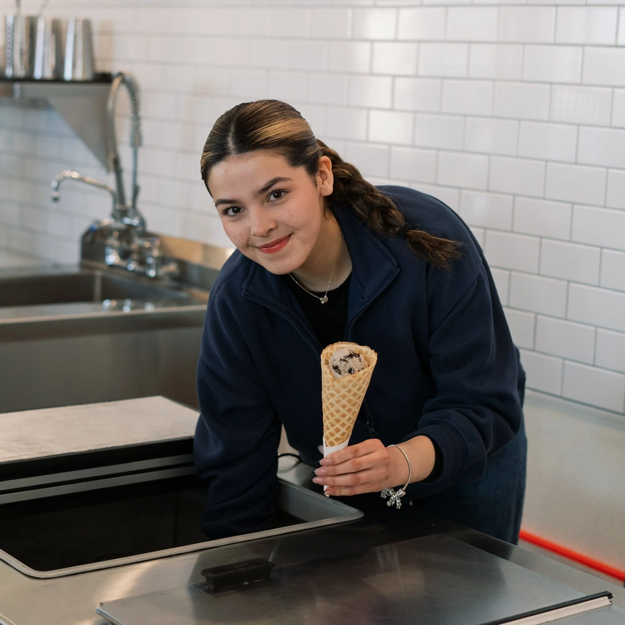 genuine ice cream employee scooping ice cream into a waffle cone
