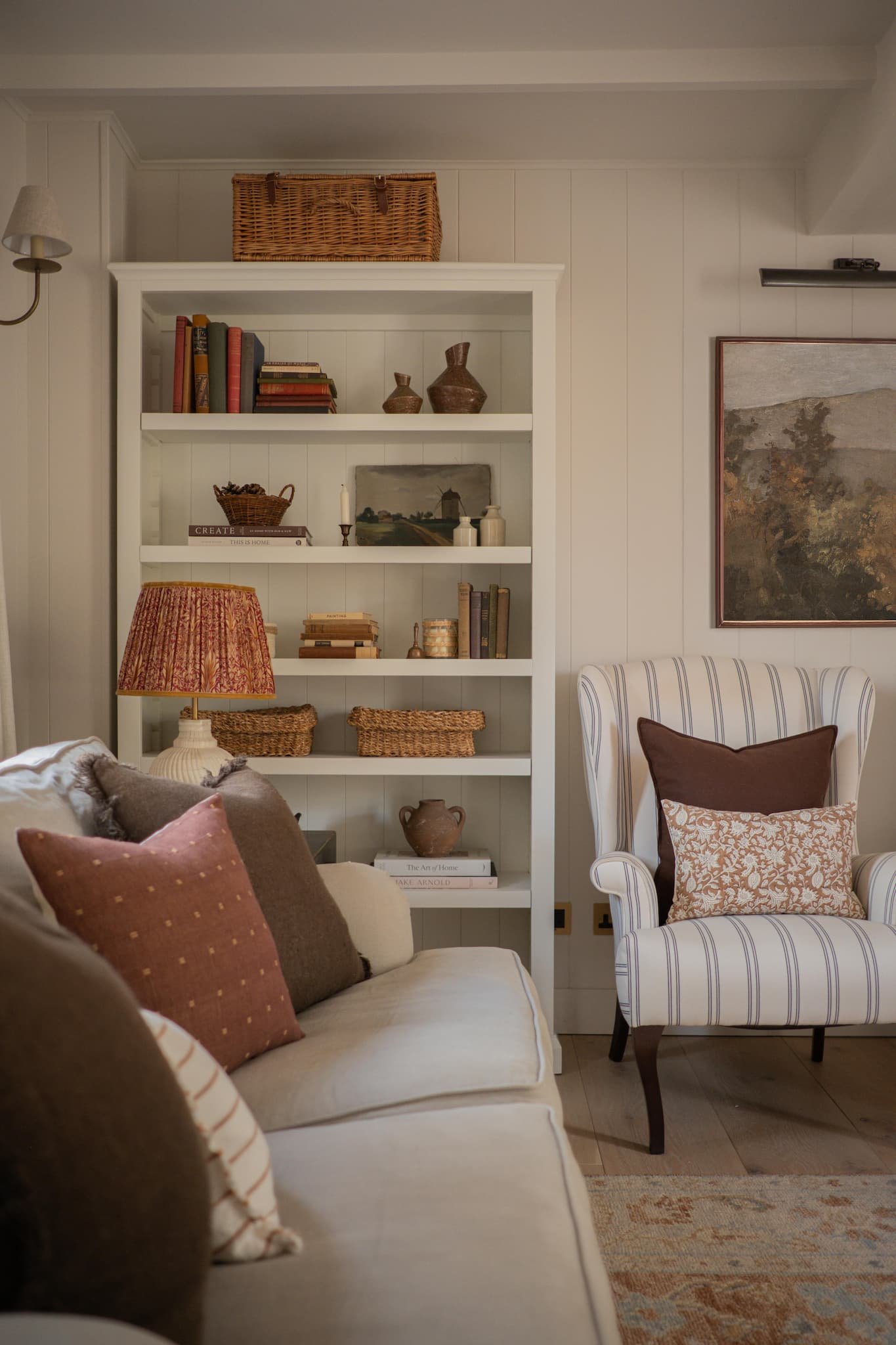 Cosy Hampshire sitting room with traditional armchairs, layered cushions, and handcrafted lighting — designed by Amy Broad Interior Design.